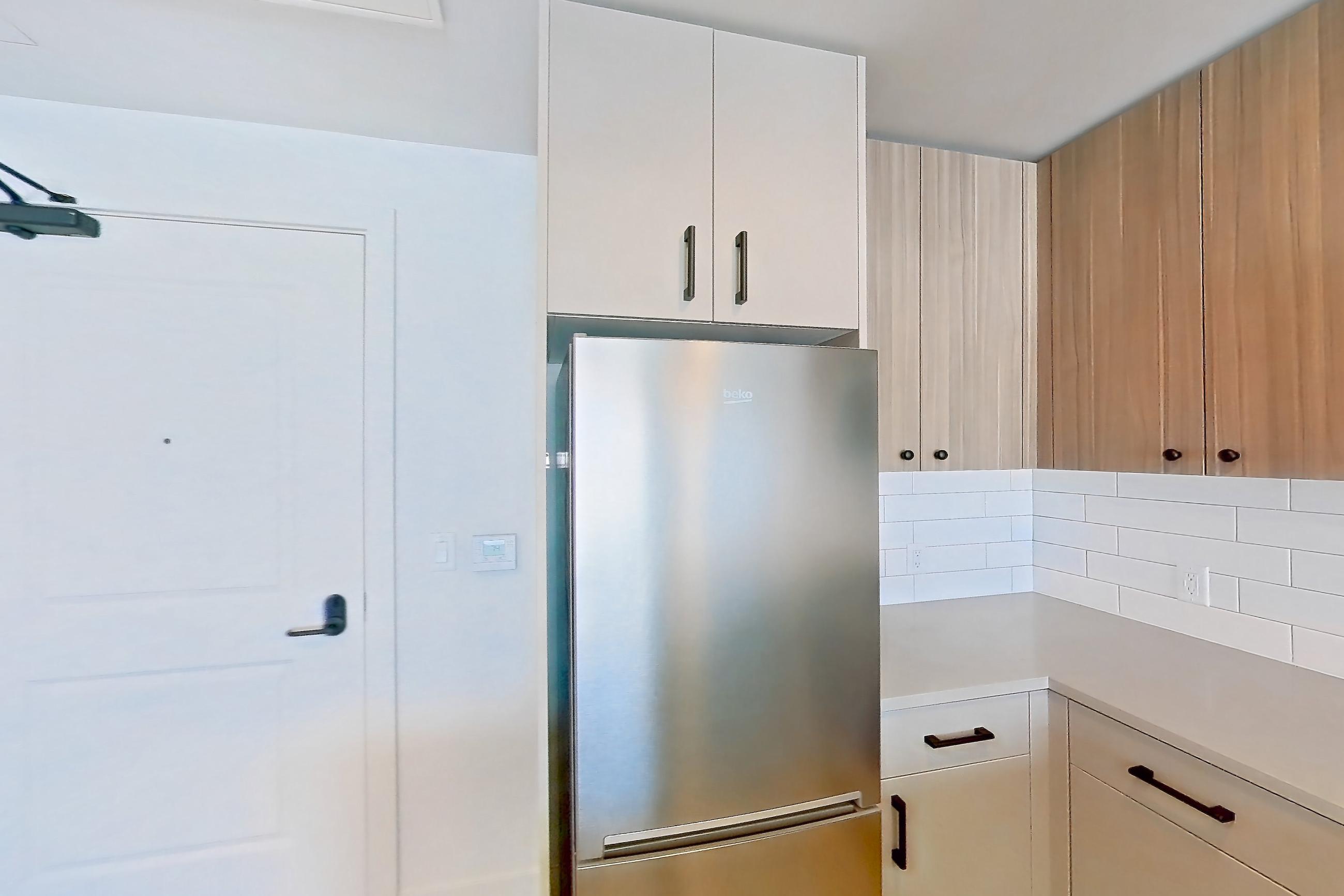 Kitchen with dishwasher, gas range, light countertops, light wood-finish flooring, oven/range, refrigerator, and stainless steel appliances, Apartment 635 at The Myles