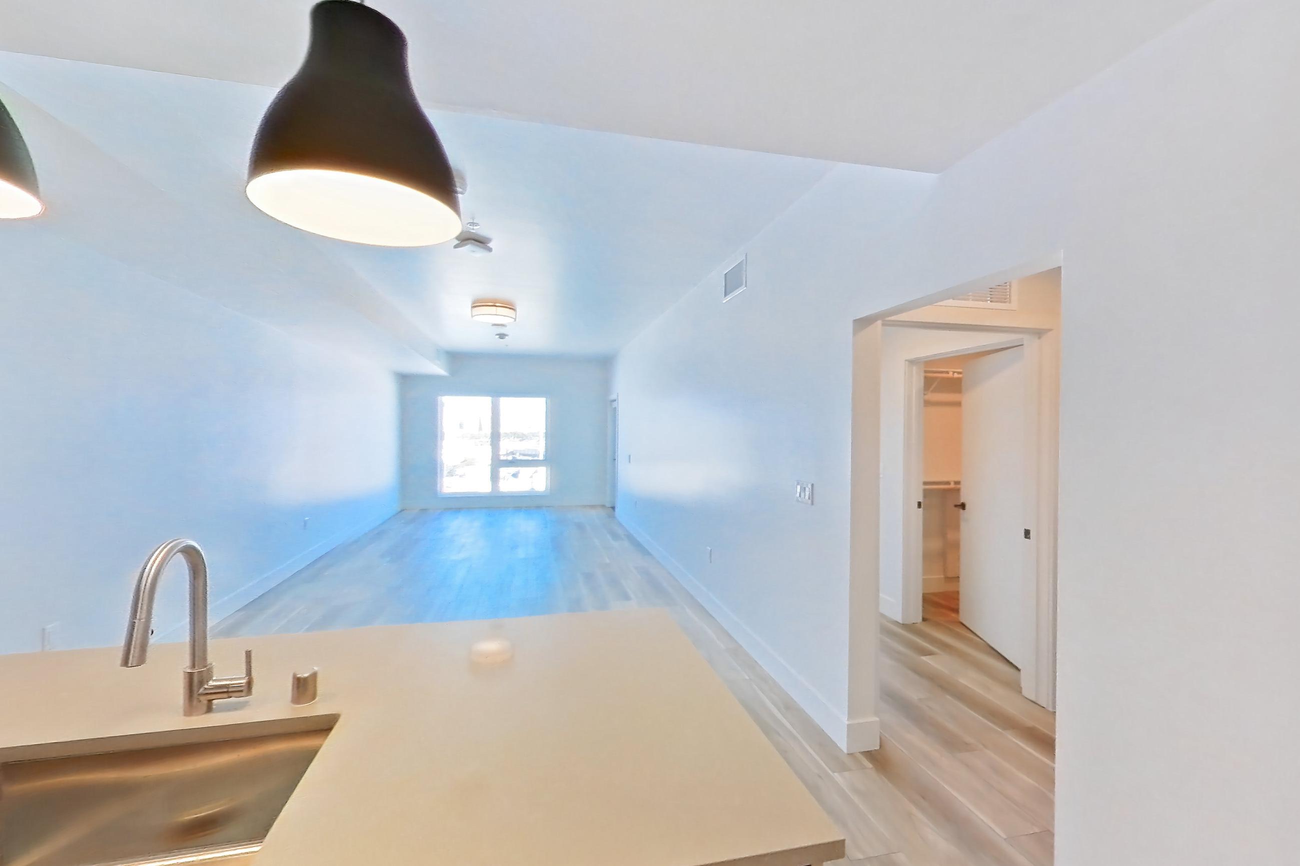 Kitchen with dishwasher, gas range, light countertops, light wood-finish flooring, oven/range, refrigerator, and stainless steel appliances, Apartment 637 at The Myles