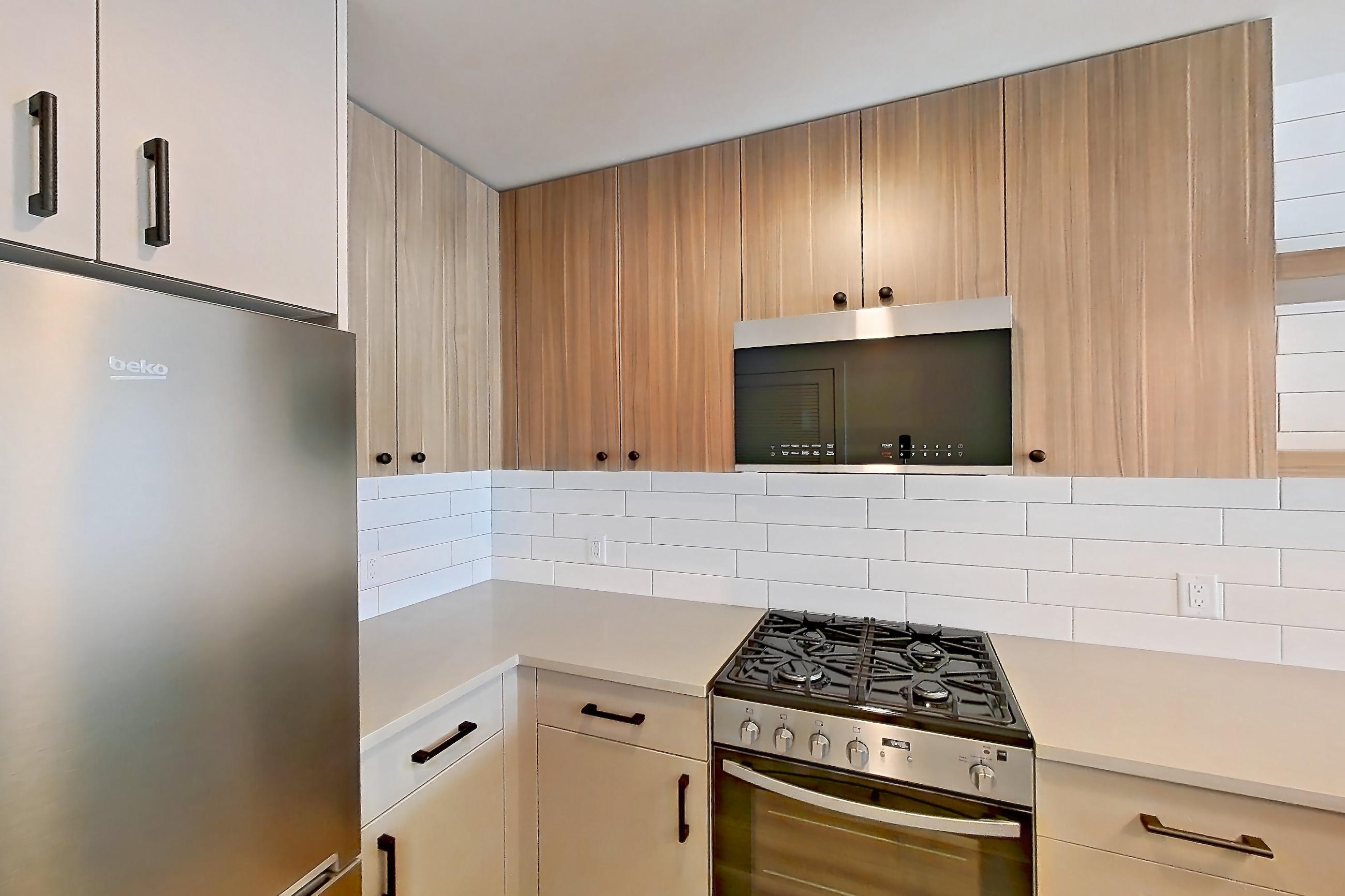 Kitchen with dishwasher, gas range, light countertops, light wood-finish flooring, oven/range, refrigerator, and stainless steel appliances, Apartment 638 at The Myles