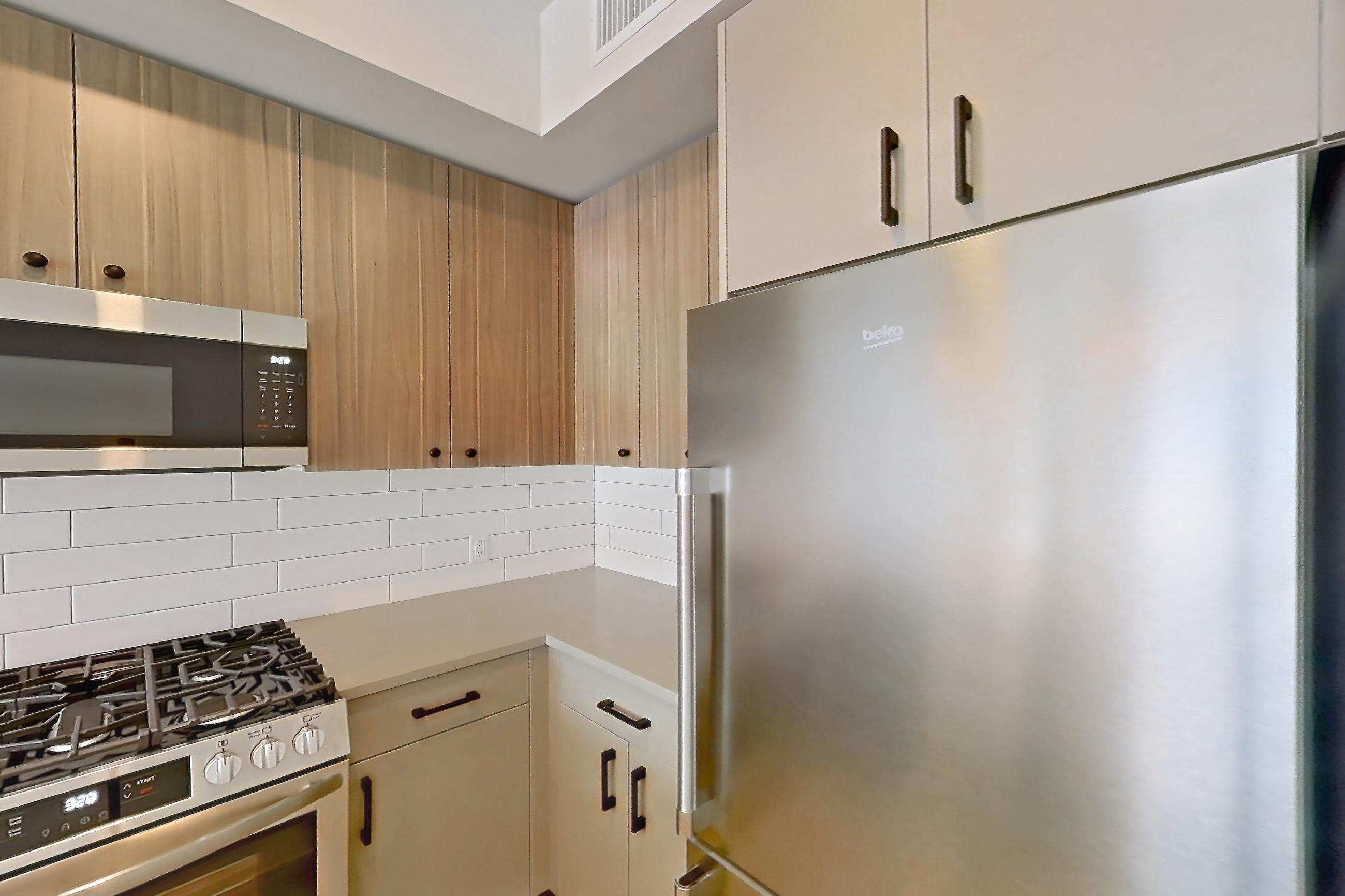 Kitchen with dishwasher, gas range, light countertops, light stone countertops, light wood-finish flooring, oven/range, and stainless steel appliances, Apartment 640 at The Myles