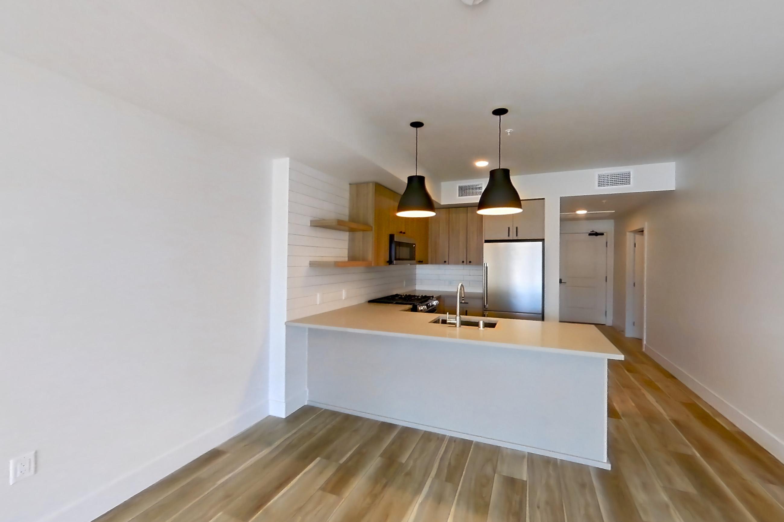 Living room with gas range, light countertops, light wood-finish flooring, oven/range, and stainless steel appliances, Apartment 640 at The Myles