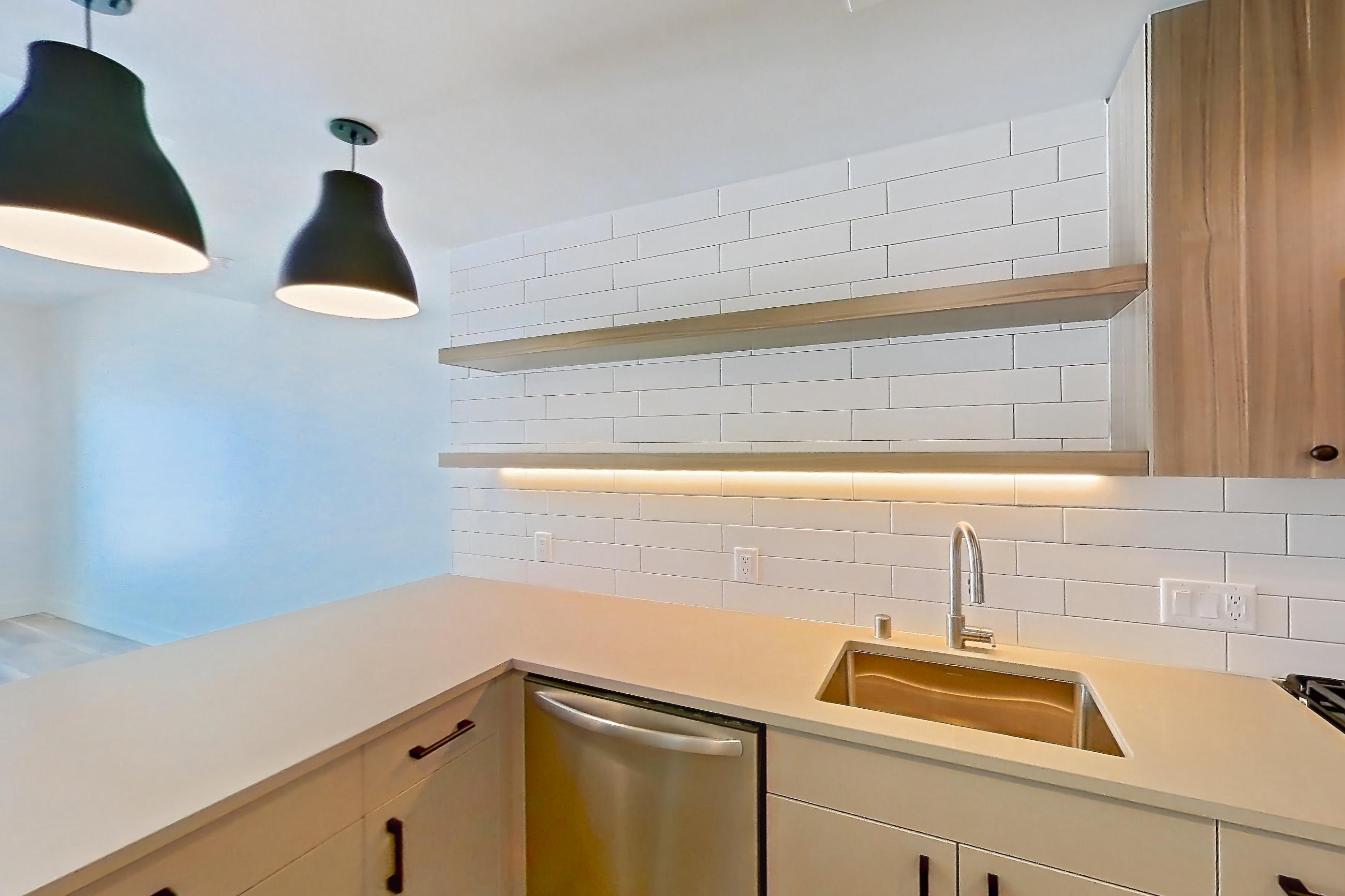 Kitchen with dishwasher, gas range, light countertops, light wood-finish flooring, microwave, oven/range, refrigerator, and stainless steel appliances, Apartment 641 at The Myles
