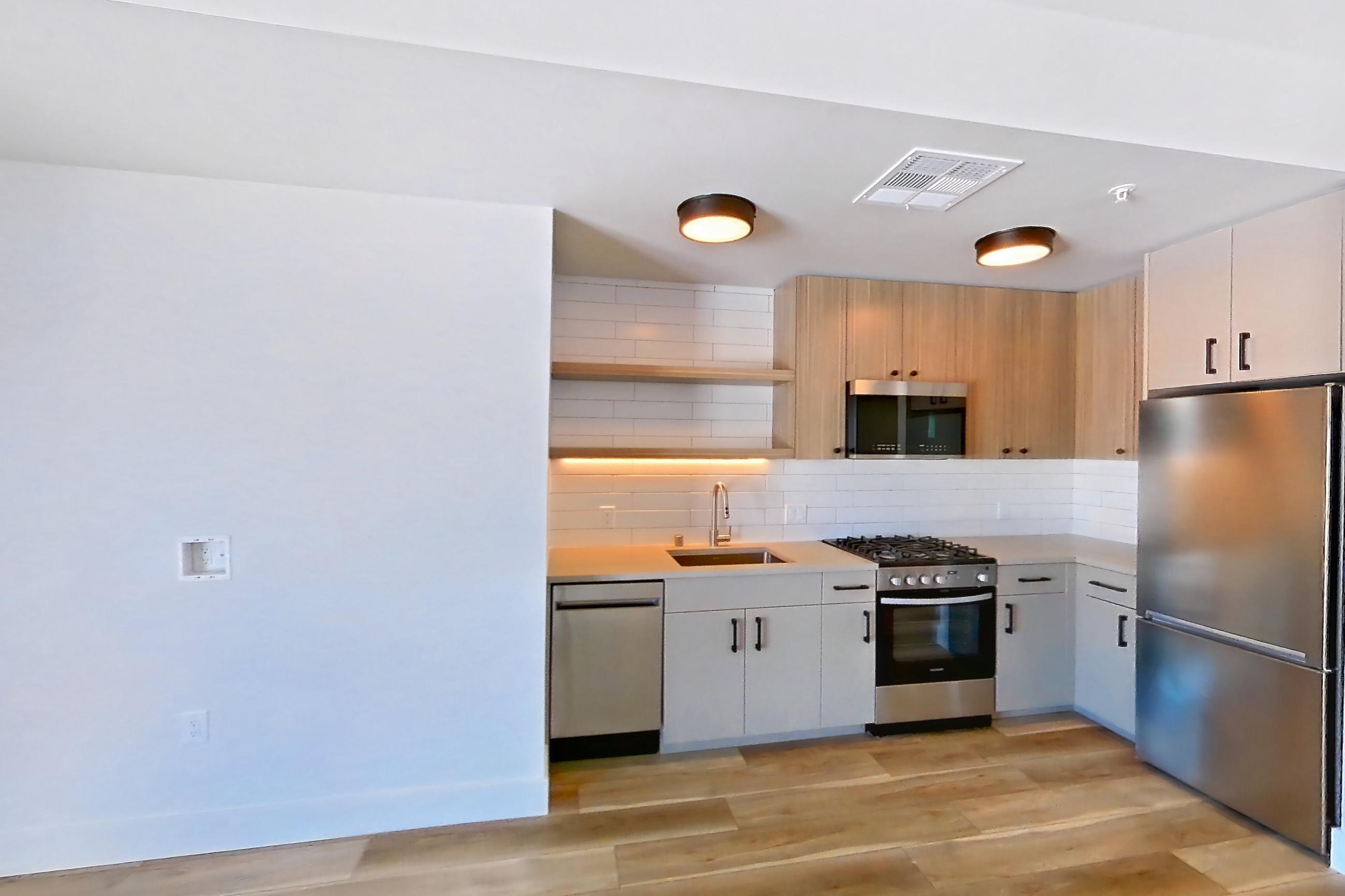 Living space with dishwasher, light countertops, light wood-finish flooring, and stainless steel appliances, Apartment 643 at The Myles