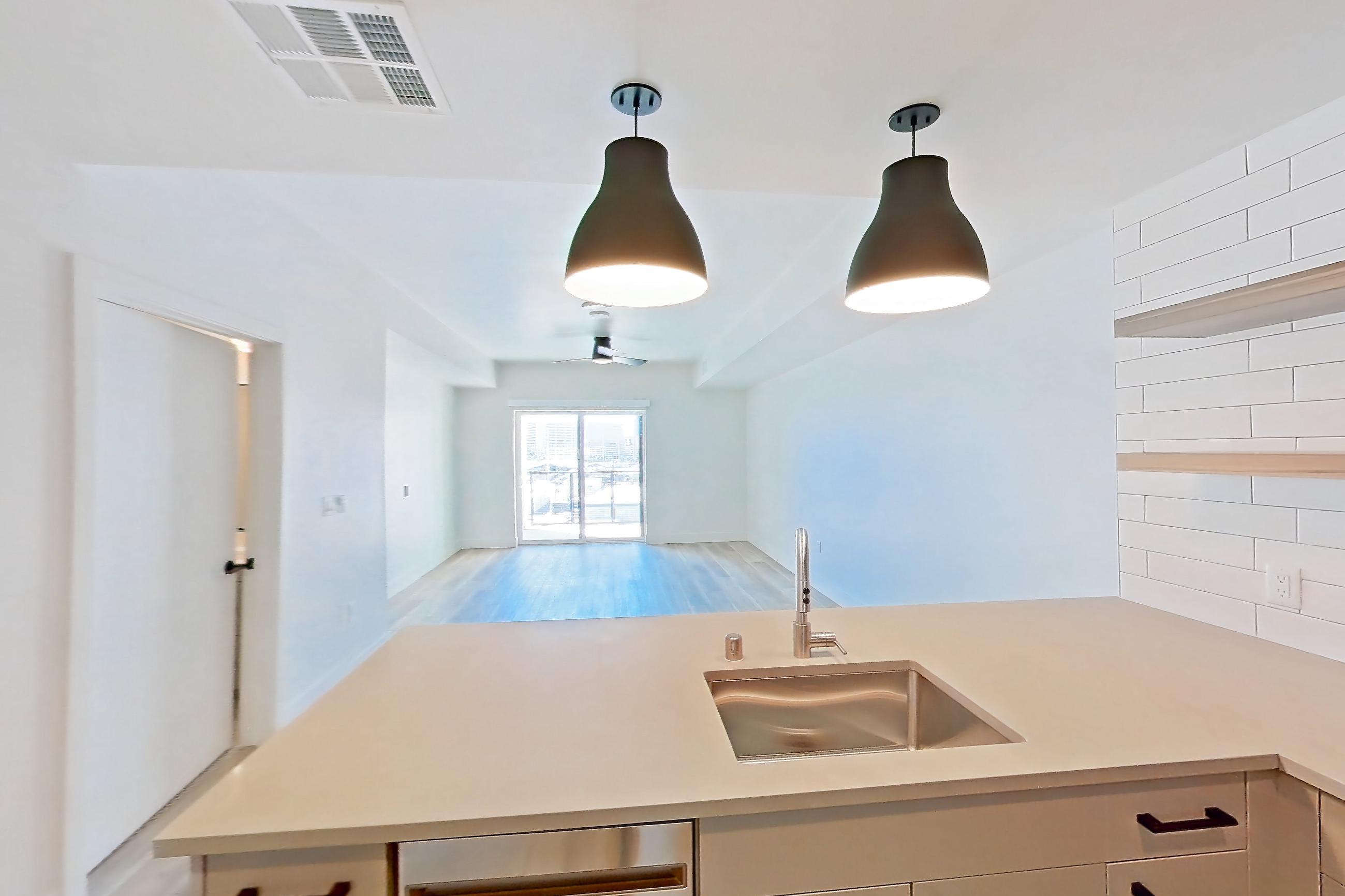 Kitchen with dishwasher, gas range, light countertops, light wood-finish flooring, oven/range, and stainless steel appliances, Apartment 644 at The Myles