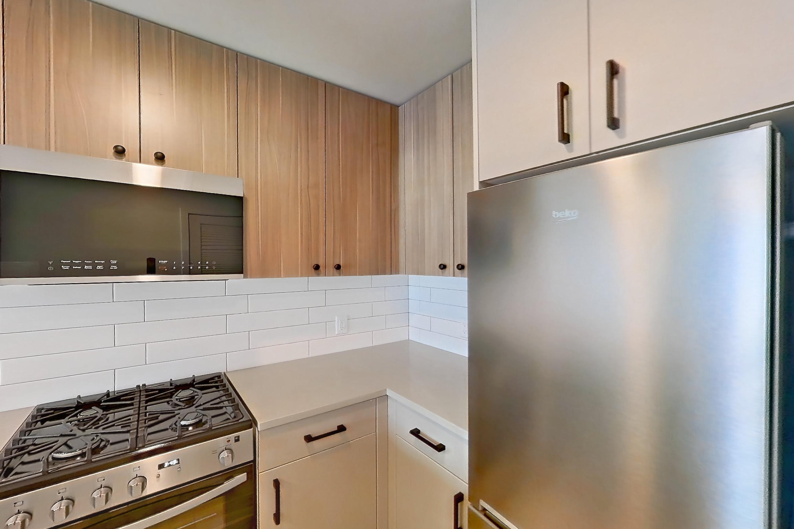 Kitchen with dishwasher, gas range, light countertops, light wood-finish flooring, oven/range, and stainless steel appliances, Apartment 644 at The Myles