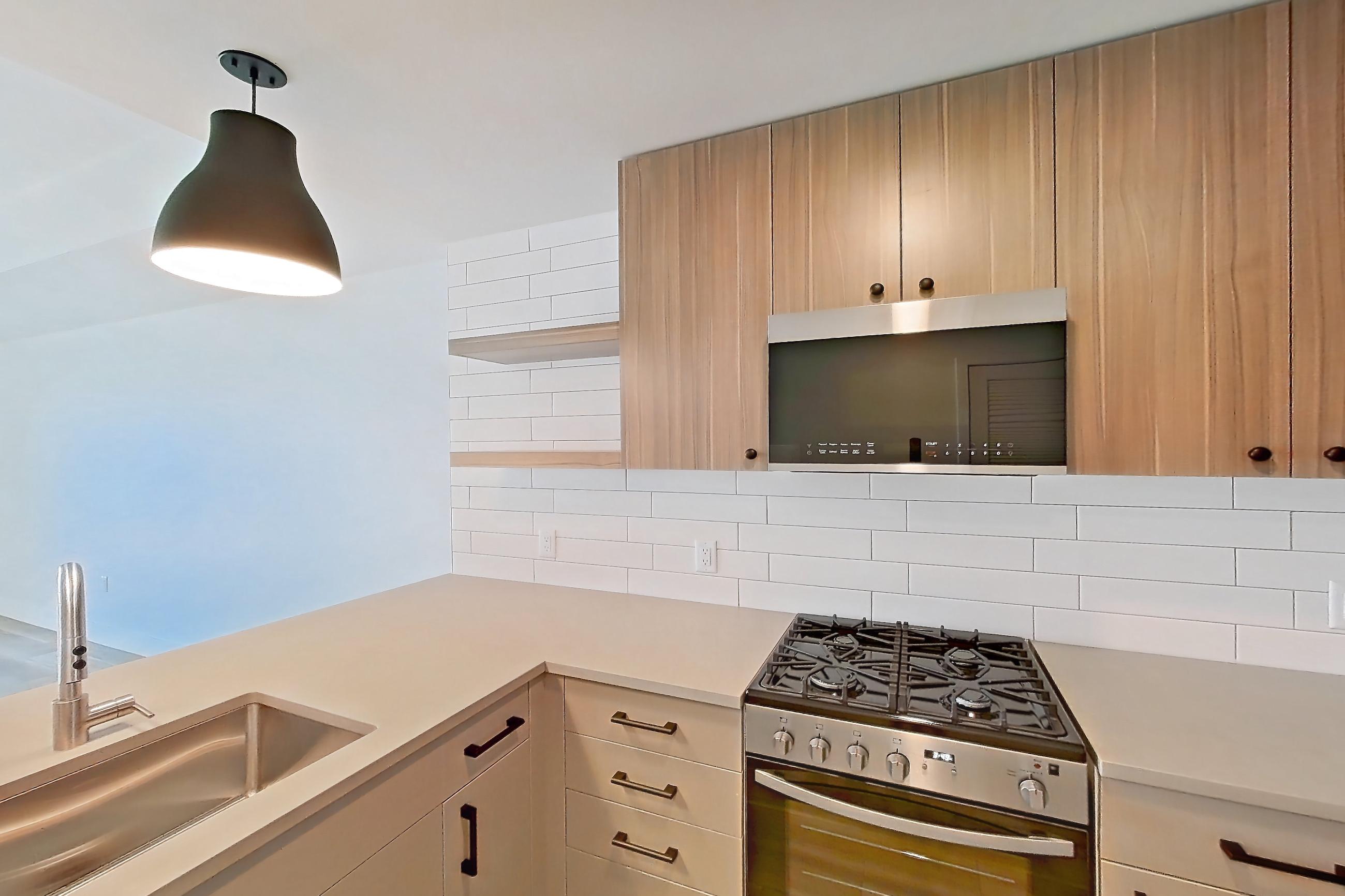 Kitchen with dishwasher, gas range, light countertops, light wood-finish flooring, oven/range, and stainless steel appliances, Apartment 644 at The Myles