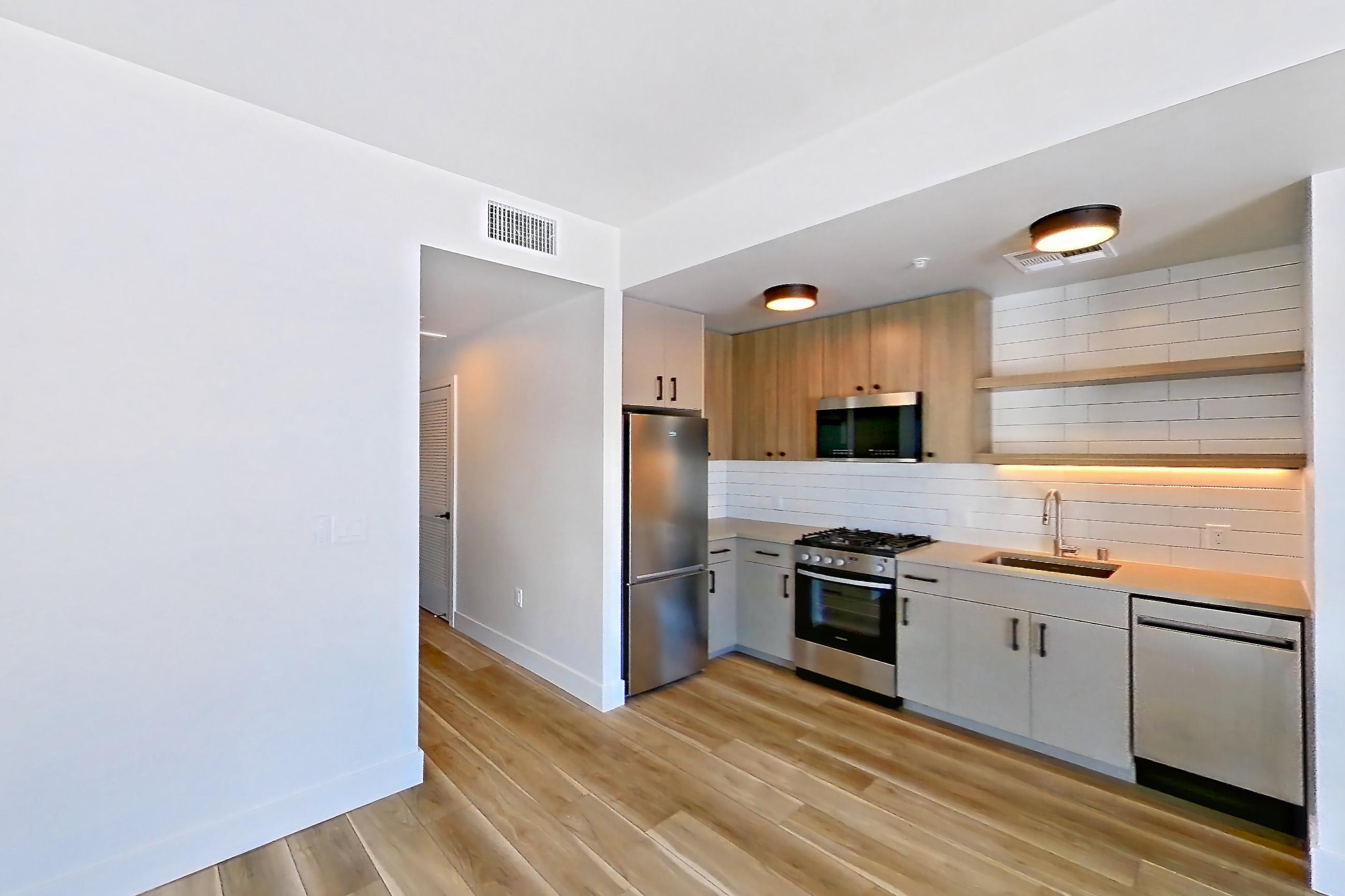 Living space with dishwasher, gas range, light countertops, light wood-finish flooring, microwave, oven/range, refrigerator, and stainless steel appliances, Apartment 645 at The Myles
