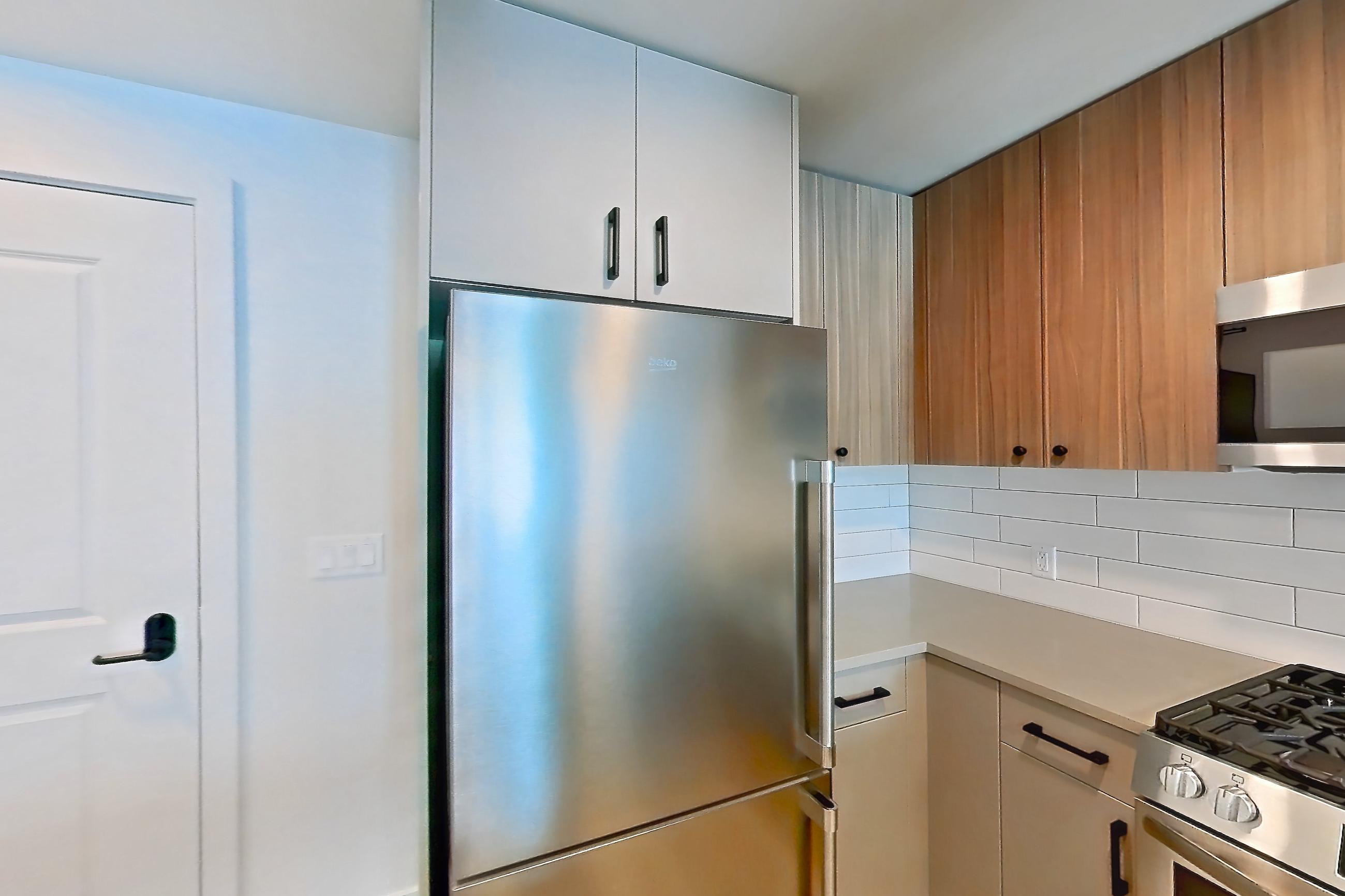 Kitchen with dishwasher, gas range, light countertops, light wood-finish flooring, microwave, oven/range, refrigerator, and stainless steel appliances, Apartment 647 at The Myles