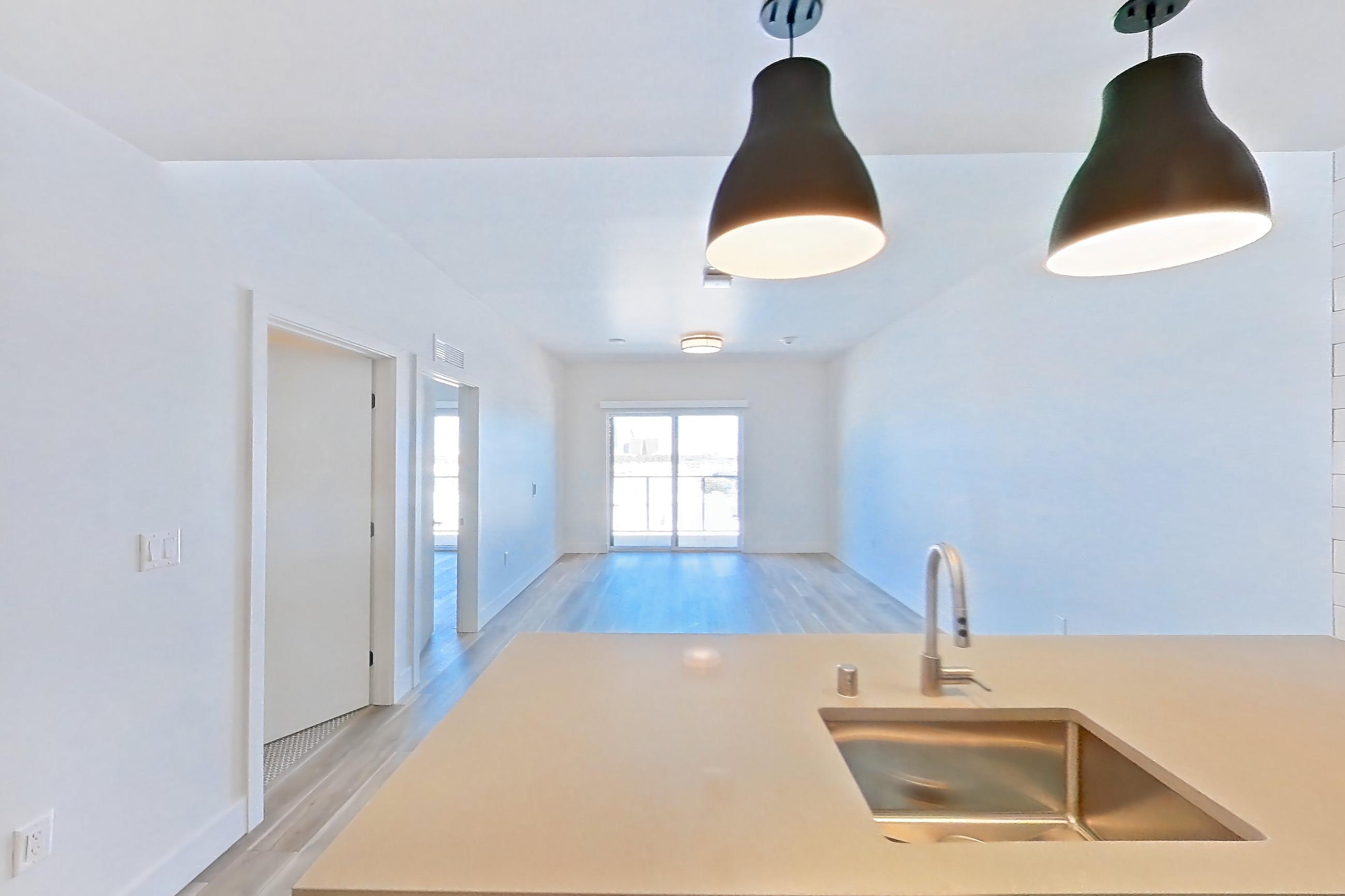 Kitchen with dishwasher, gas range, light countertops, light wood-finish flooring, oven/range, refrigerator, and stainless steel appliances, Apartment 648 at The Myles