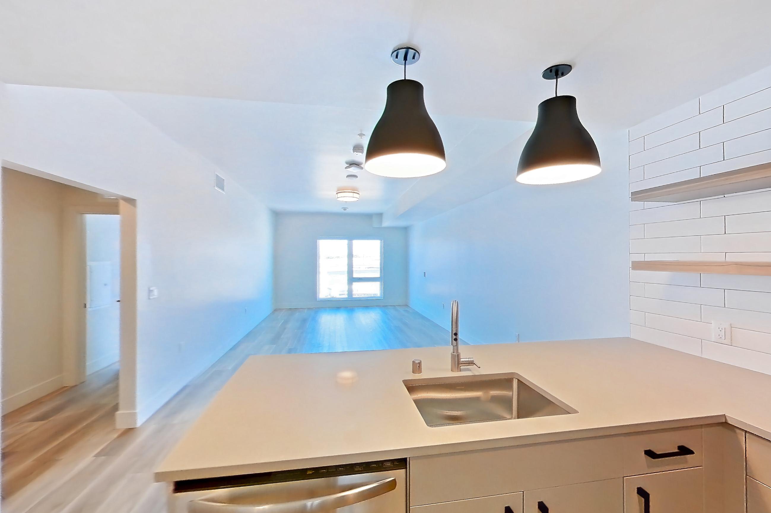 Kitchen with dishwasher, gas range, light countertops, light wood-finish flooring, oven/range, refrigerator, and stainless steel appliances, Apartment 650 at The Myles