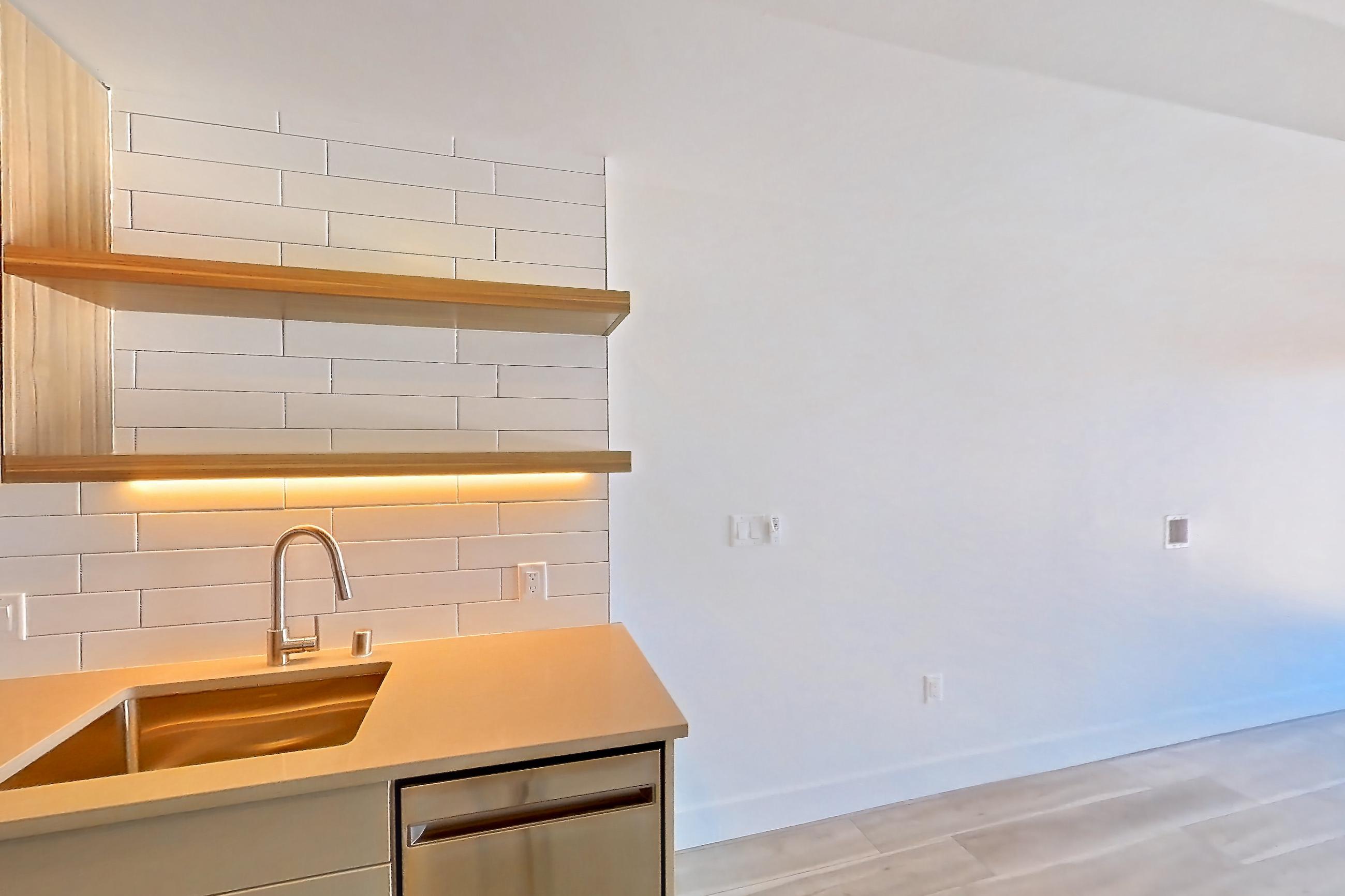 Kitchen with dishwasher, gas range, light countertops, light wood-finish flooring, oven/range, refrigerator, and stainless steel appliances, Apartment 651 at The Myles