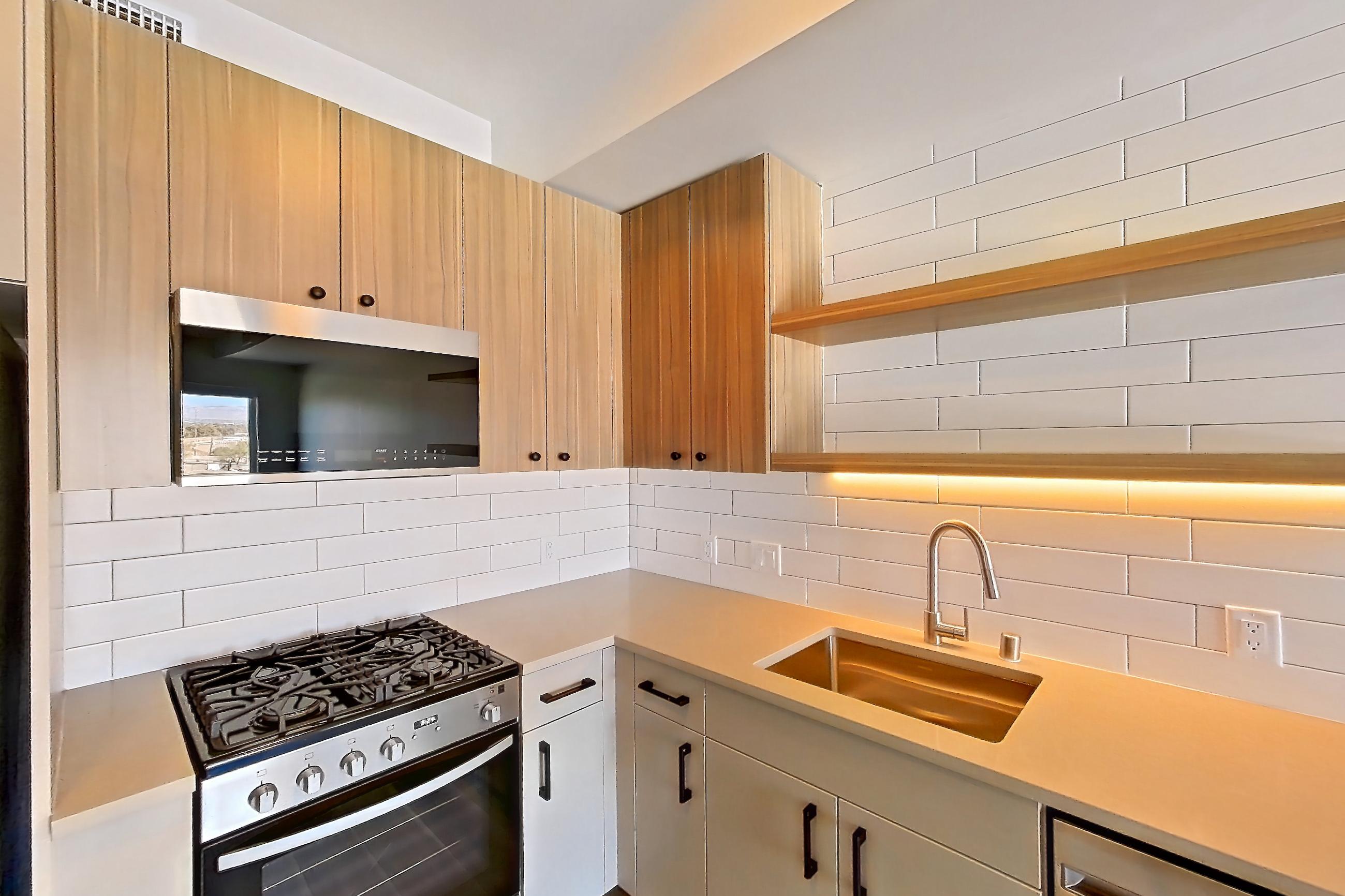 Kitchen with dishwasher, gas range, light countertops, light wood-finish flooring, oven/range, refrigerator, and stainless steel appliances, Apartment 651 at The Myles