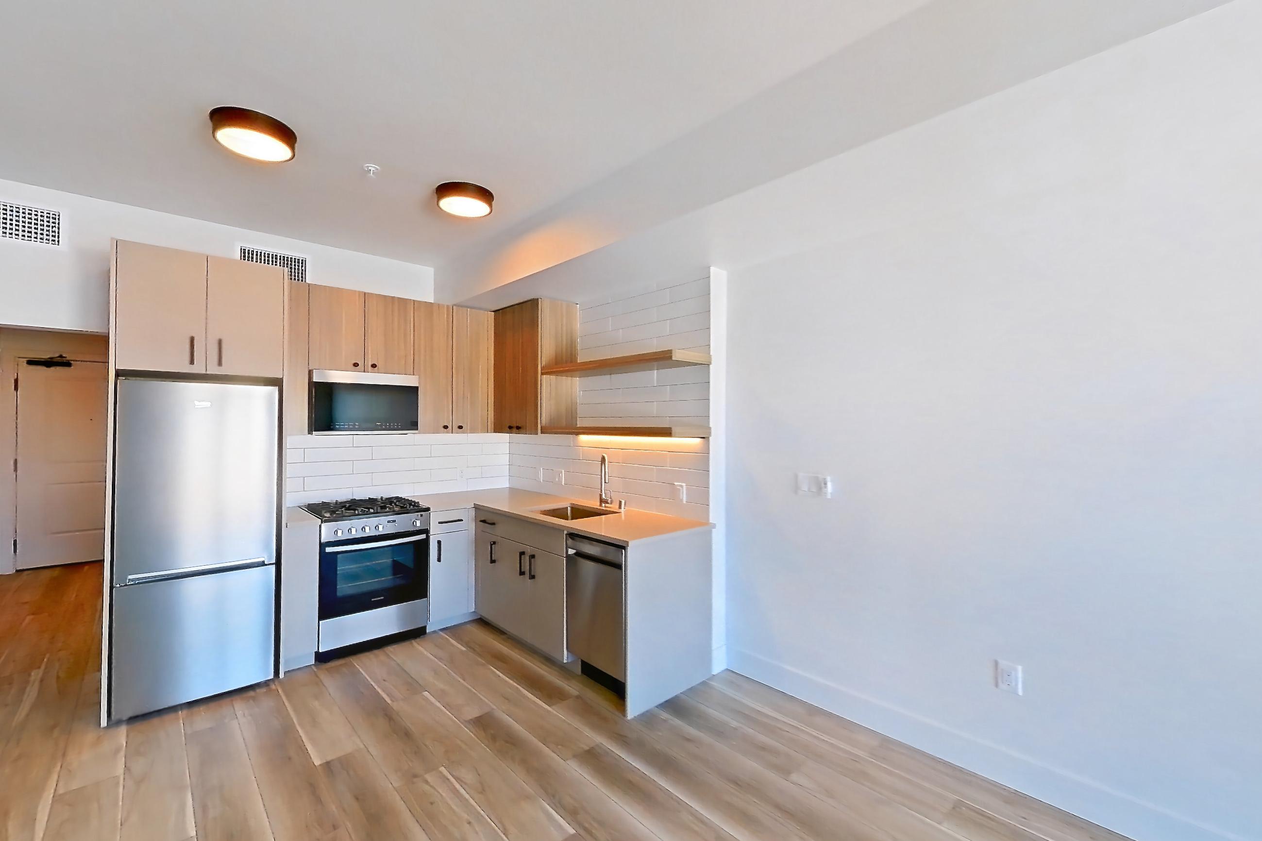 Living space with dishwasher, light wood-finish flooring, and stainless steel appliances, Apartment 651 at The Myles