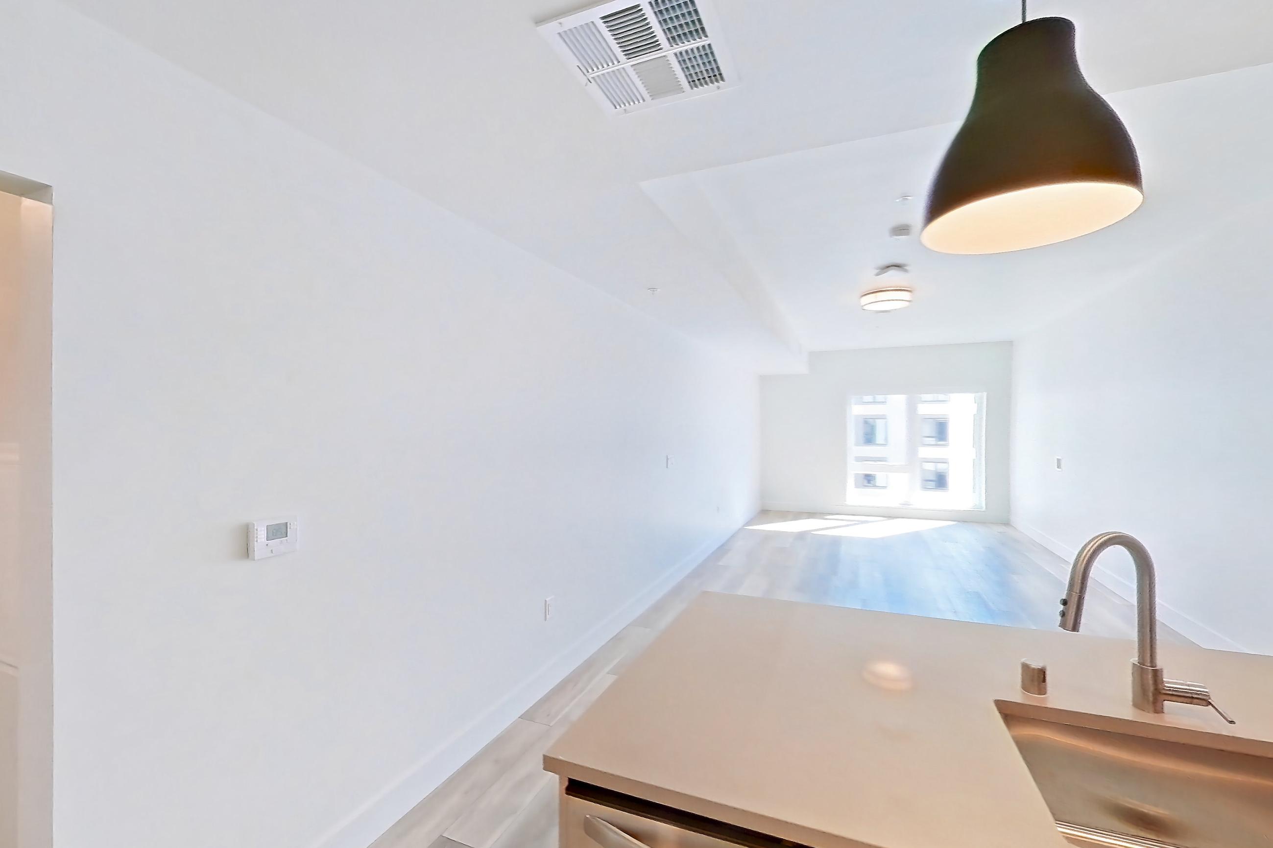 Kitchen with dishwasher, gas range, light countertops, light wood-finish flooring, microwave, oven/range, refrigerator, stainless steel appliances, and wood-look tile flooring, Apartment 652 at The Myles