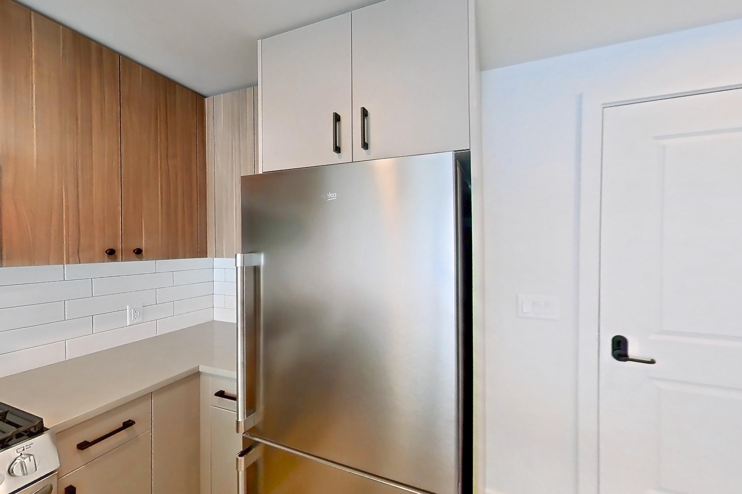 Kitchen with dishwasher, gas range, light countertops, light wood-finish flooring, microwave, oven/range, refrigerator, stainless steel appliances, and wood-look tile flooring, Apartment 652 at The Myles