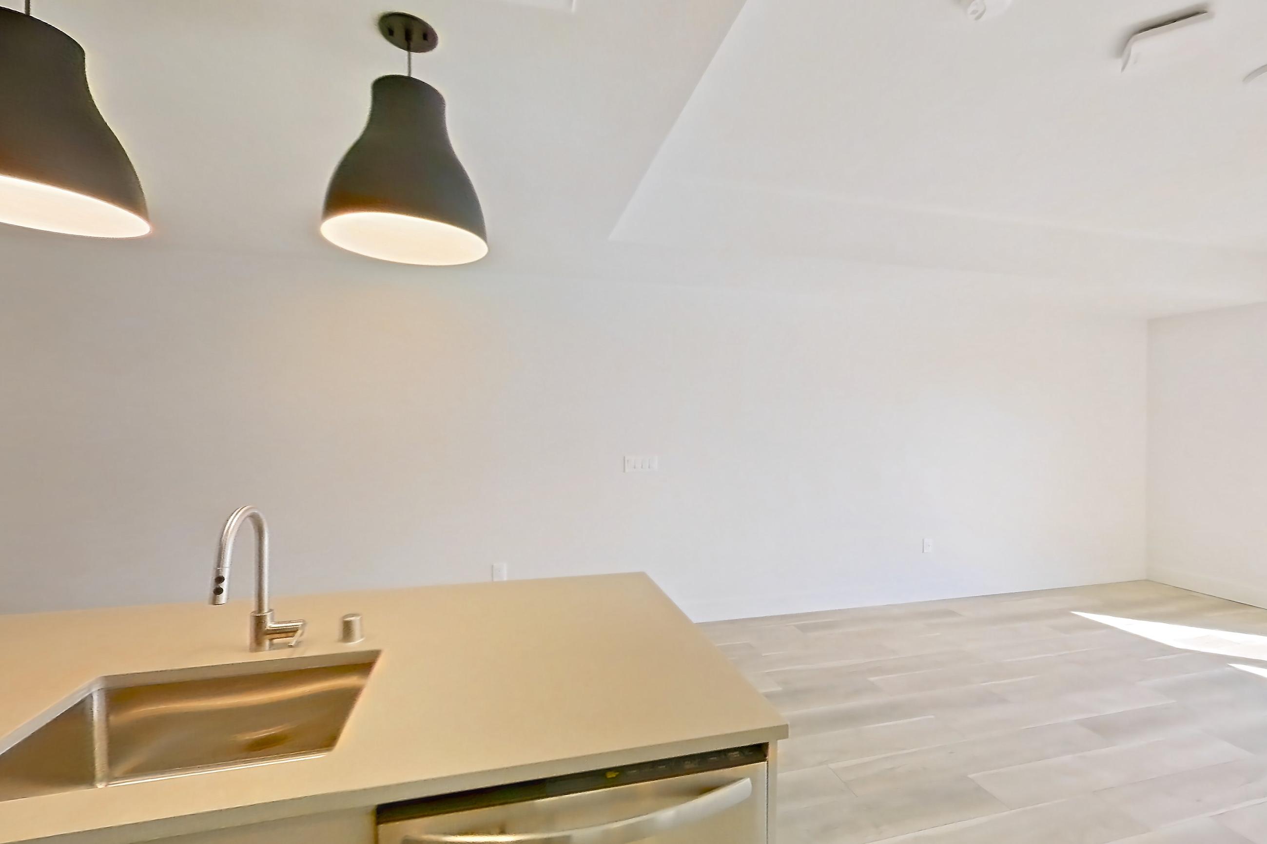 Kitchen with dishwasher, gas range, light countertops, light wood-finish flooring, oven/range, refrigerator, and stainless steel appliances, Apartment 654 at The Myles