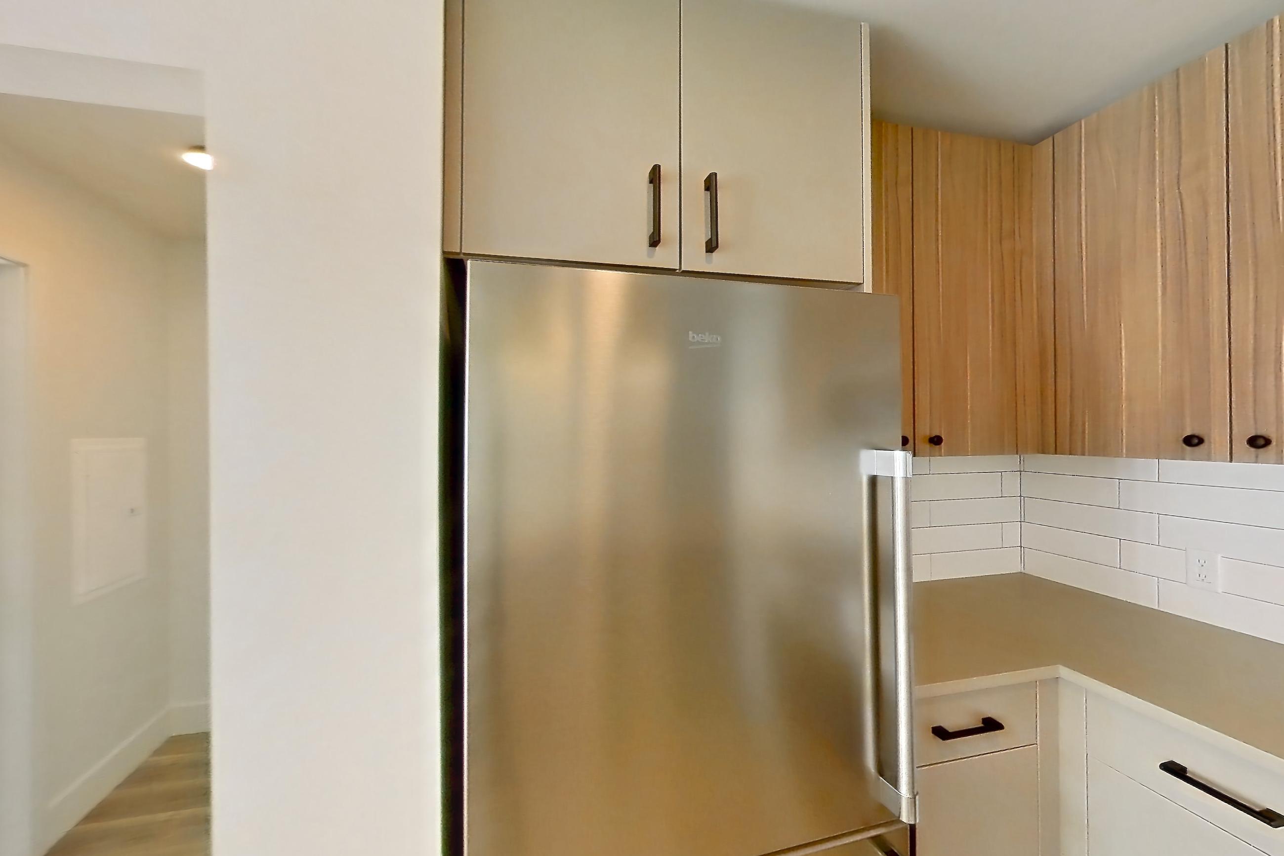 Kitchen with dishwasher, gas range, light countertops, light wood-finish flooring, oven/range, refrigerator, and stainless steel appliances, Apartment 654 at The Myles