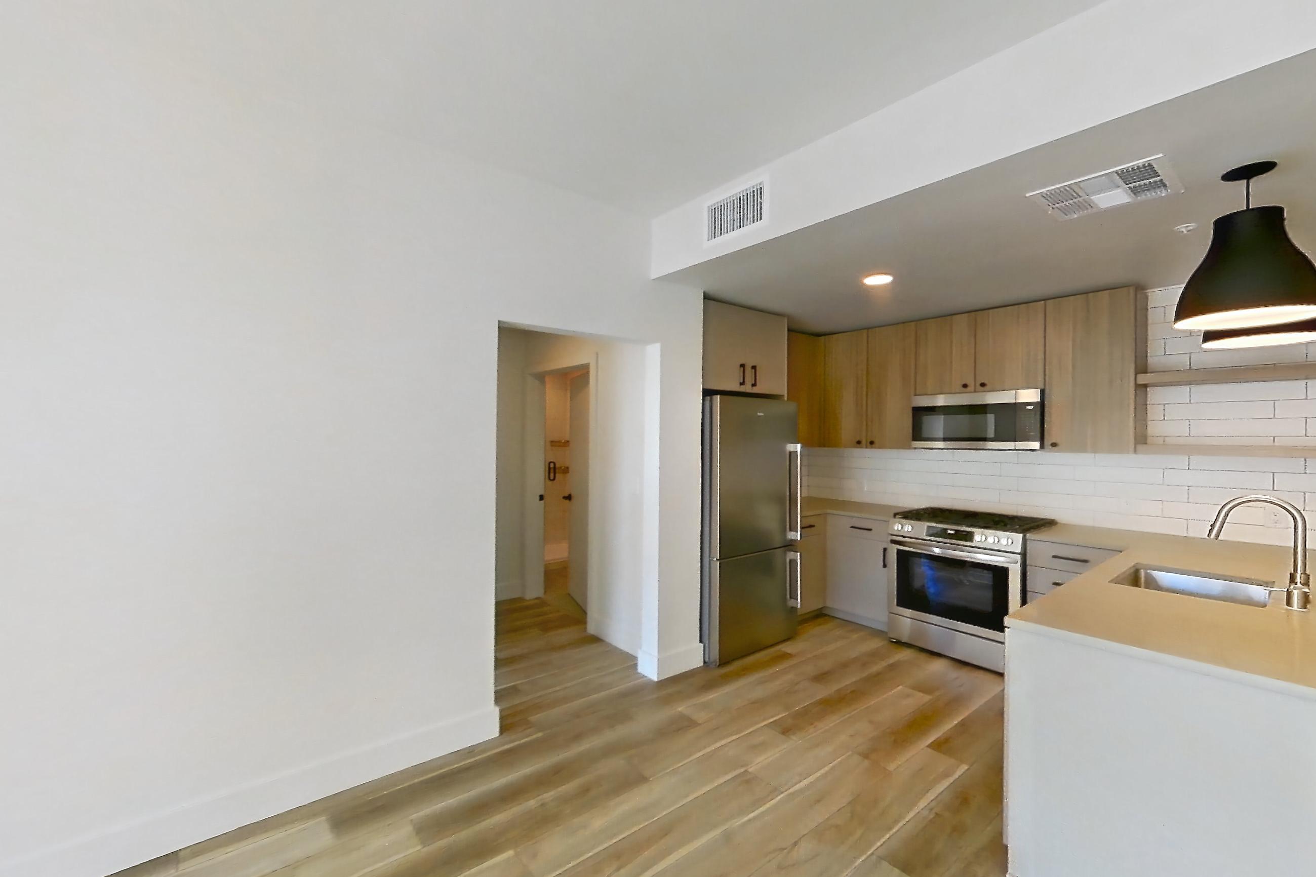 Living room with light wood-finish flooring, refrigerator, stainless steel appliances, and wood-look tile flooring, Apartment 654 at The Myles