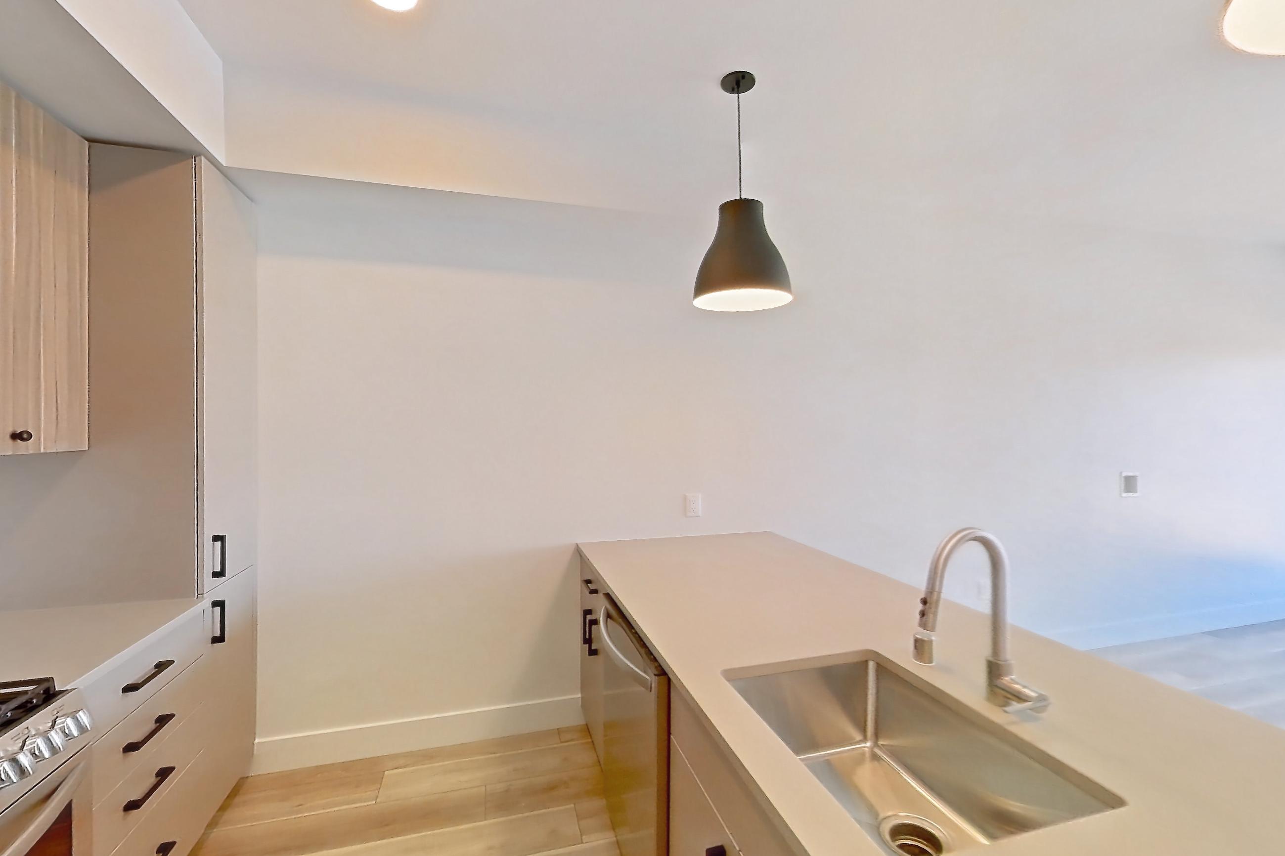 Kitchen with dishwasher, gas range, light countertops, light wood-finish flooring, microwave, oven/range, and stainless steel appliances, Apartment 655 at The Myles