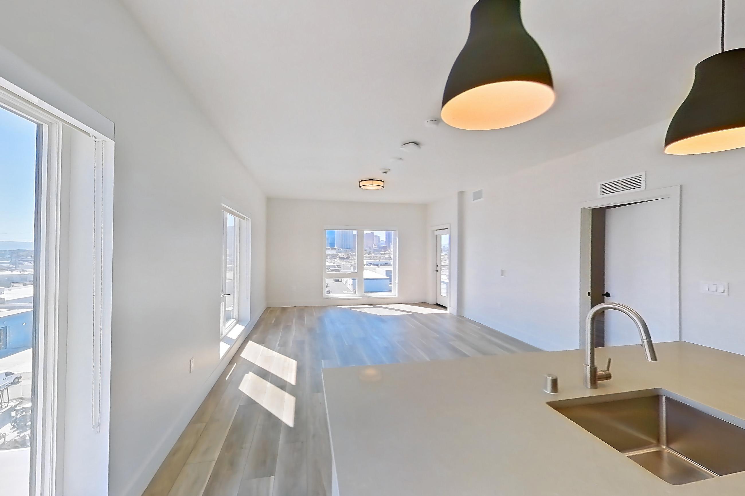 Kitchen with dishwasher, gas range, kitchen island, light countertops, light stone countertops, light wood-finish flooring, microwave, oven/range, refrigerator, stainless steel appliances, and wood-look tile flooring, Apartment 658 at The Myles