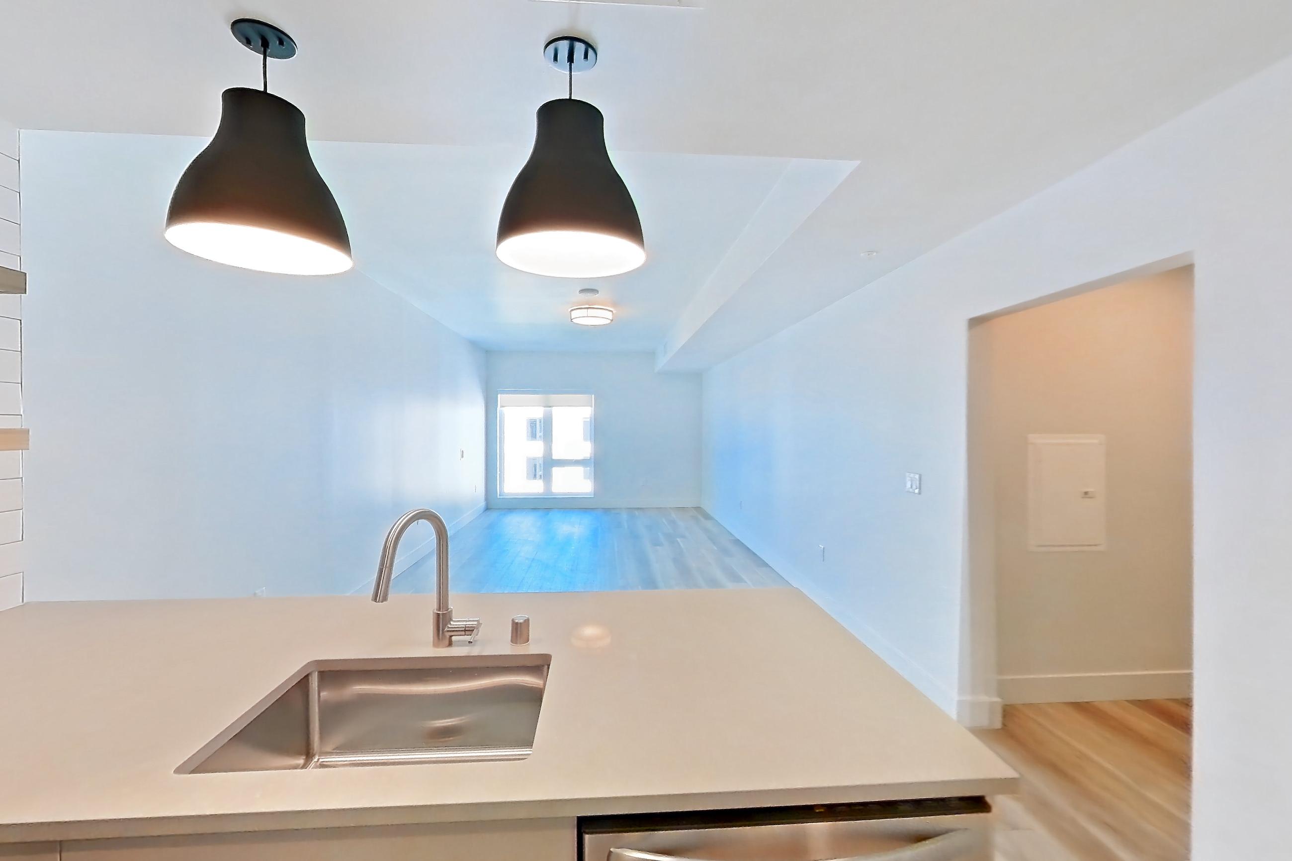 Kitchen with dishwasher, gas range, light countertops, light wood-finish flooring, microwave, oven/range, refrigerator, and stainless steel appliances, Apartment 702 at The Myles