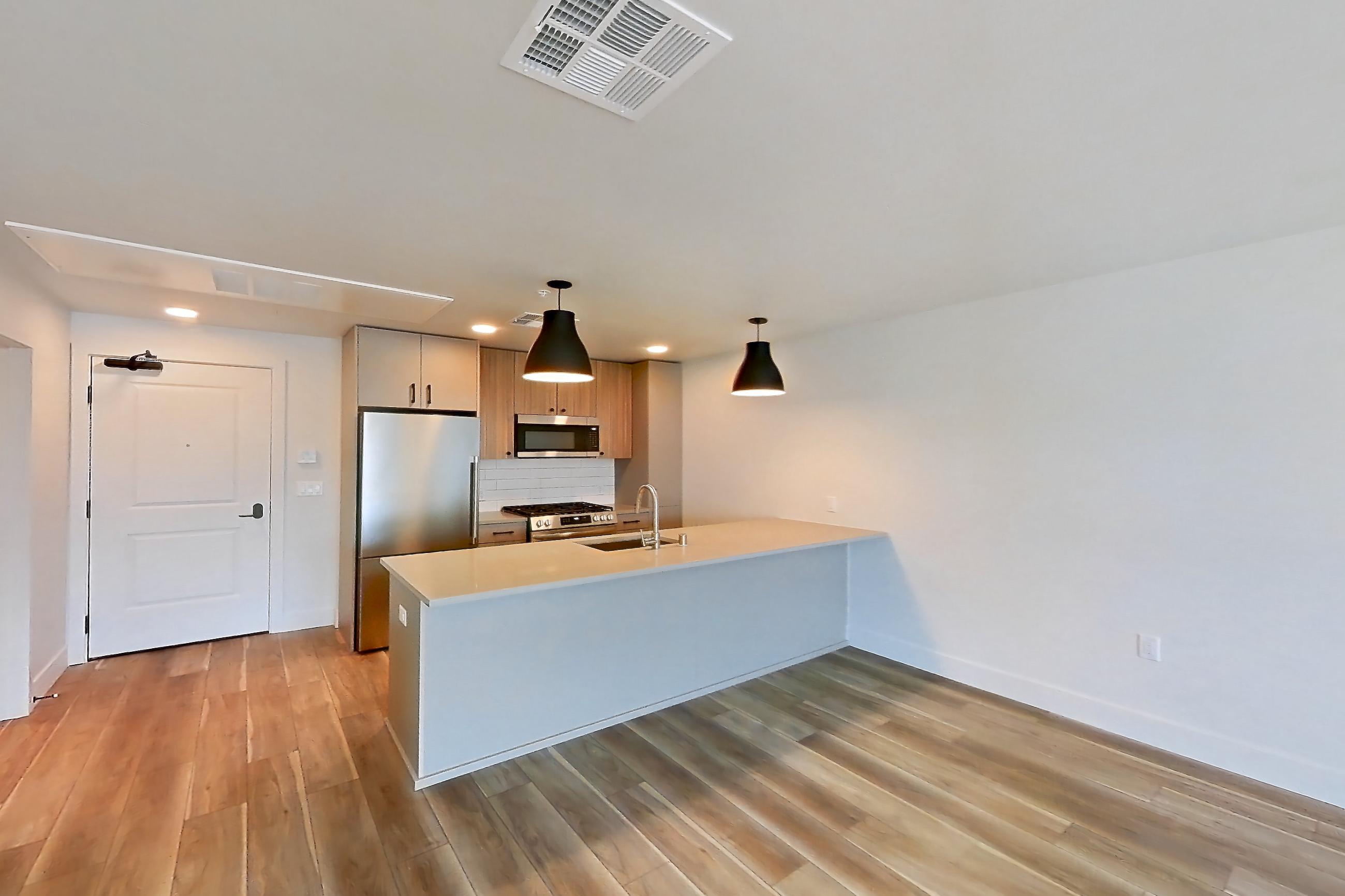 Living room with gas range, light countertops, light wood-finish flooring, oven/range, and stainless steel appliances, Apartment 703 at The Myles
