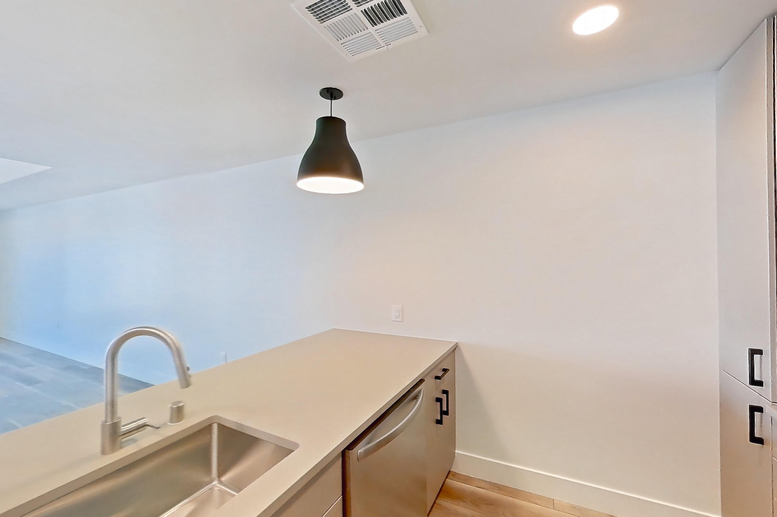 Kitchen with dishwasher, gas range, light countertops, light wood-finish flooring, microwave, oven/range, and stainless steel appliances, Apartment 704 at The Myles