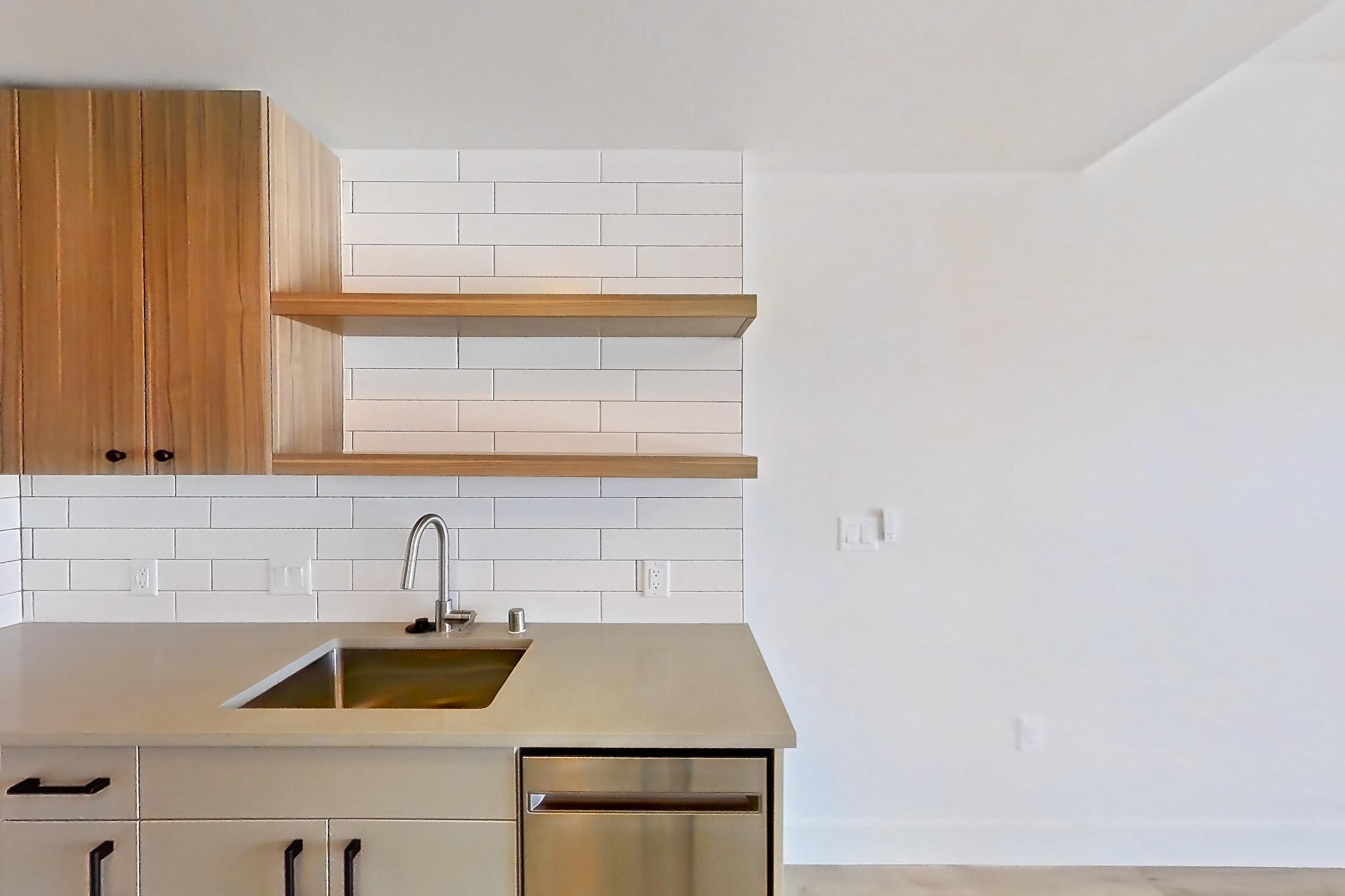 Kitchen with dishwasher, gas range, light countertops, light wood-finish flooring, oven/range, refrigerator, and stainless steel appliances, Apartment 708 at The Myles