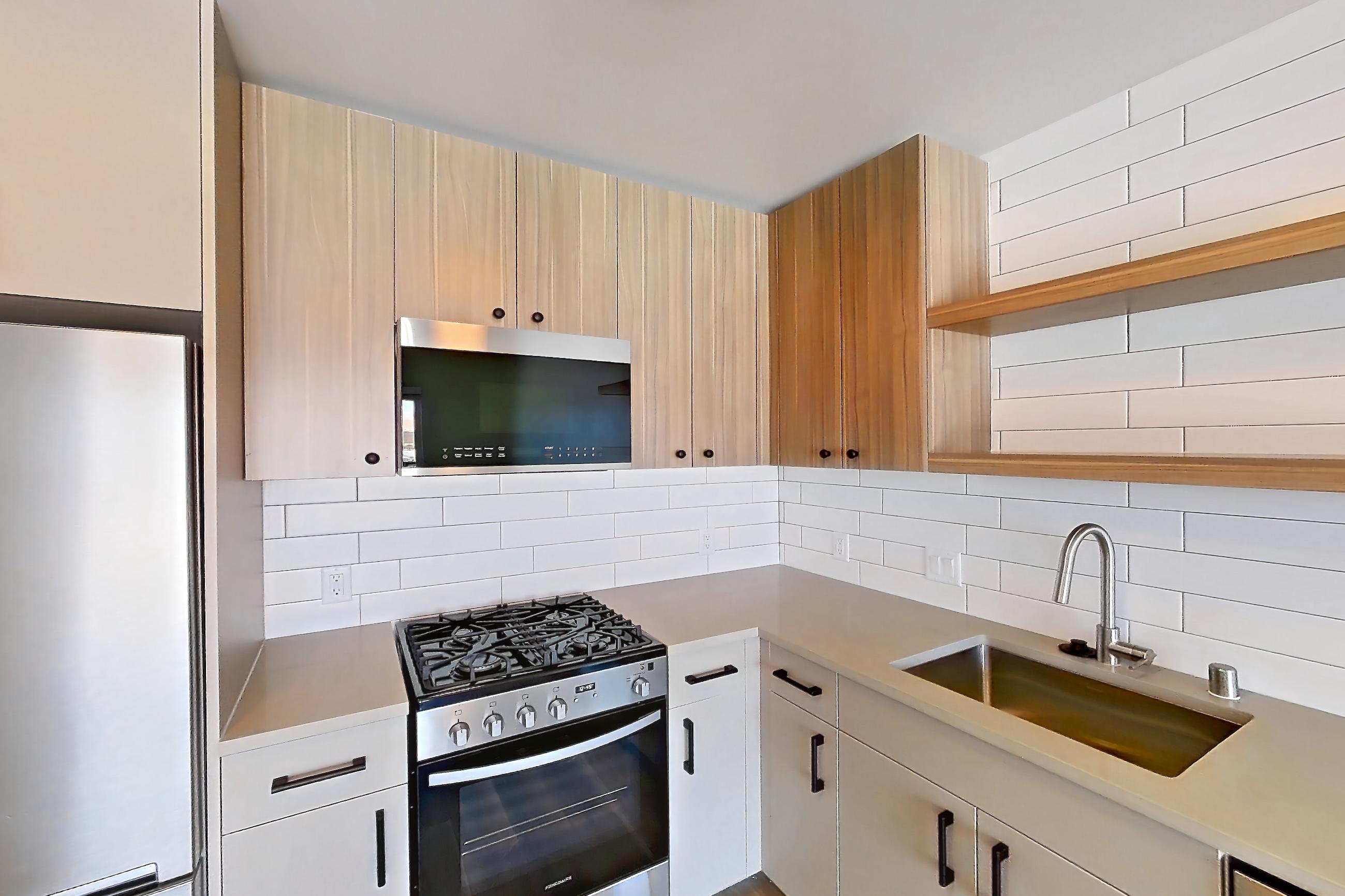 Kitchen with dishwasher, gas range, light countertops, light wood-finish flooring, oven/range, refrigerator, and stainless steel appliances, Apartment 708 at The Myles