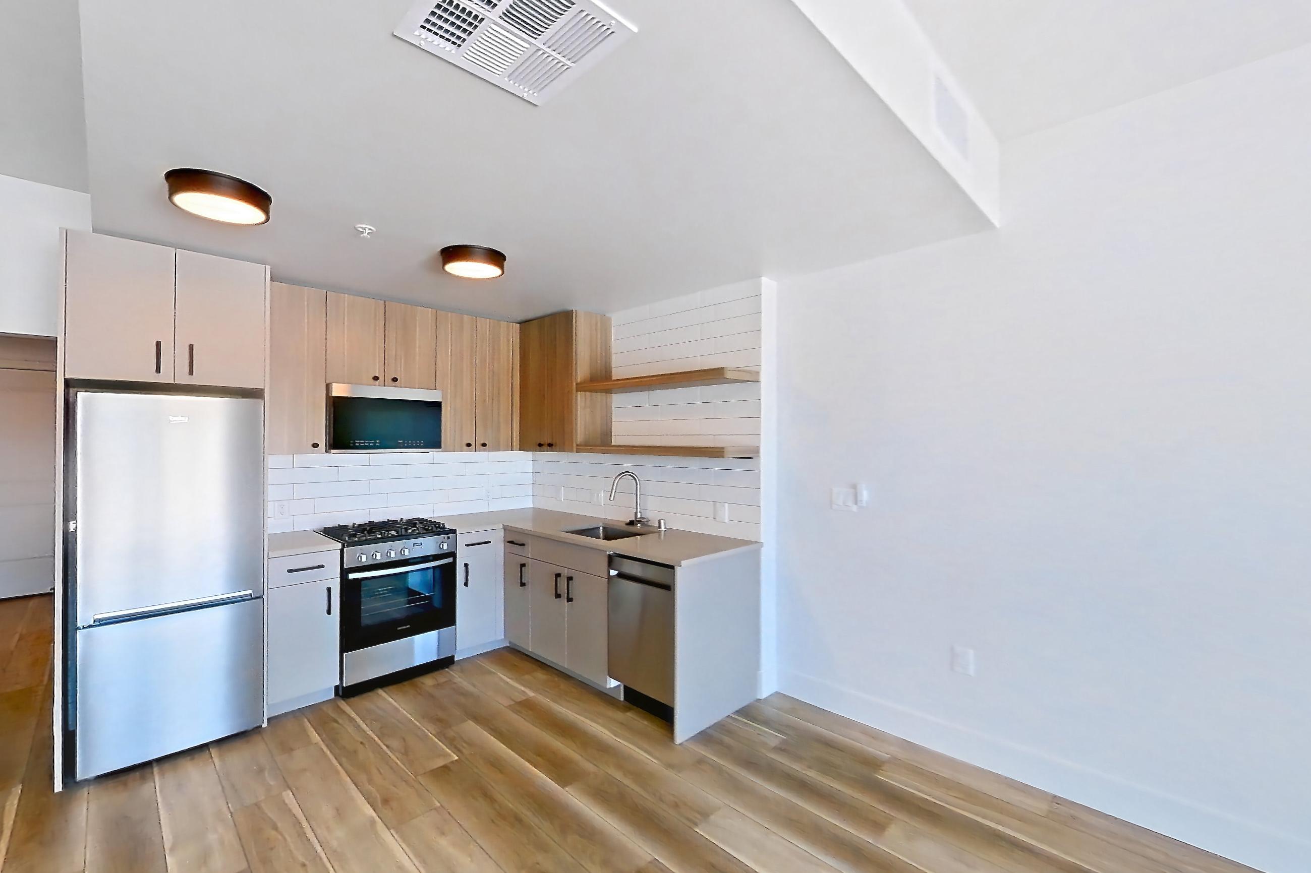 Living space with dishwasher, light wood-finish flooring, and stainless steel appliances, Apartment 708 at The Myles