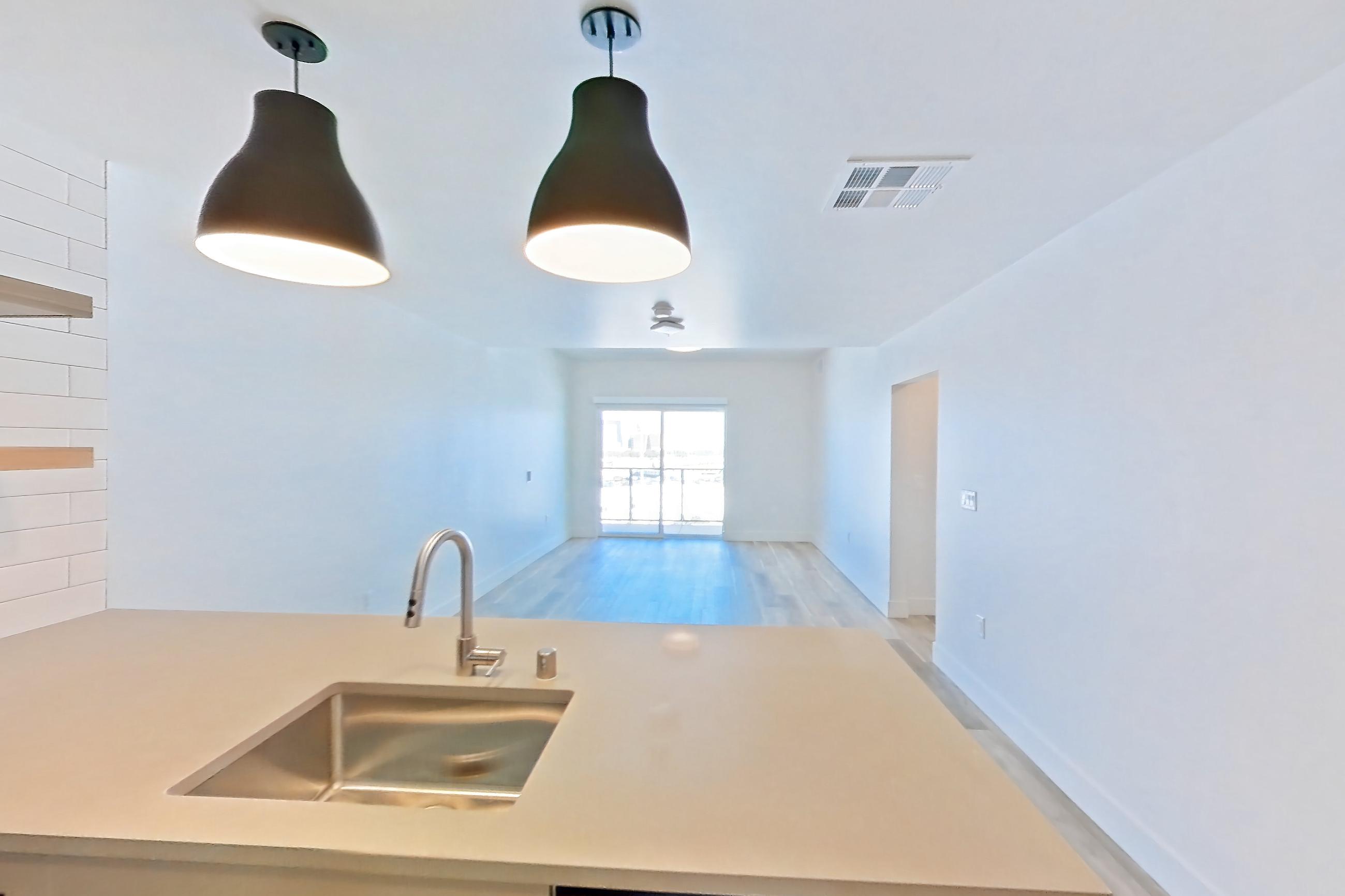 Kitchen with dishwasher, gas range, light countertops, light wood-finish flooring, oven/range, refrigerator, and stainless steel appliances, Apartment 712 at The Myles