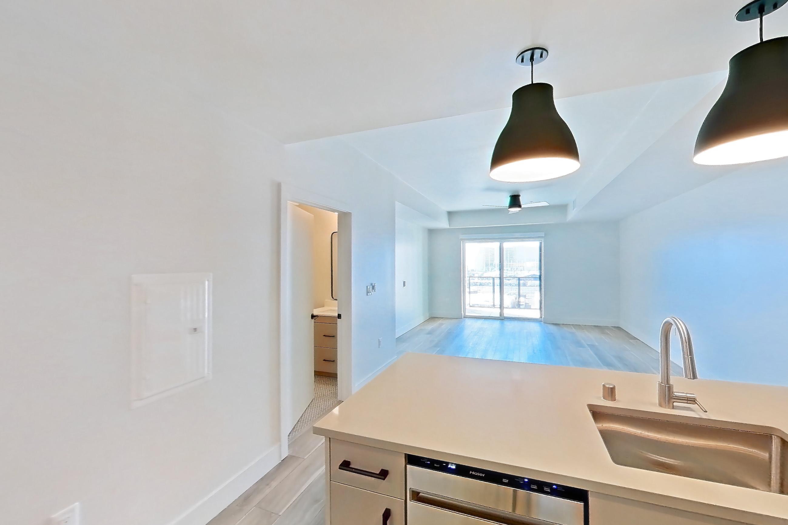 Kitchen with dishwasher, gas range, light countertops, light wood-finish flooring, oven/range, refrigerator, and stainless steel appliances, Apartment 713 at The Myles