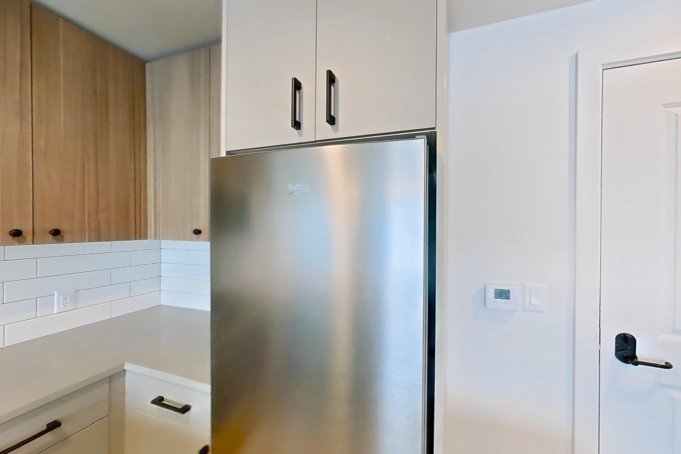 Kitchen with dishwasher, gas range, light countertops, light wood-finish flooring, oven/range, refrigerator, and stainless steel appliances, Apartment 713 at The Myles