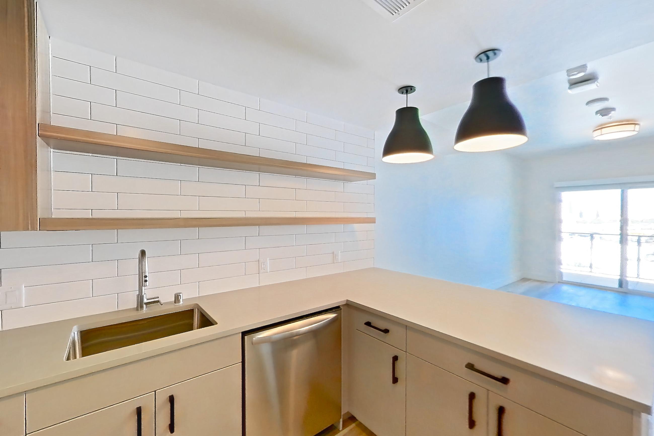 Kitchen with dishwasher, gas range, light countertops, light wood-finish flooring, microwave, oven/range, refrigerator, and stainless steel appliances, Apartment 716 at The Myles