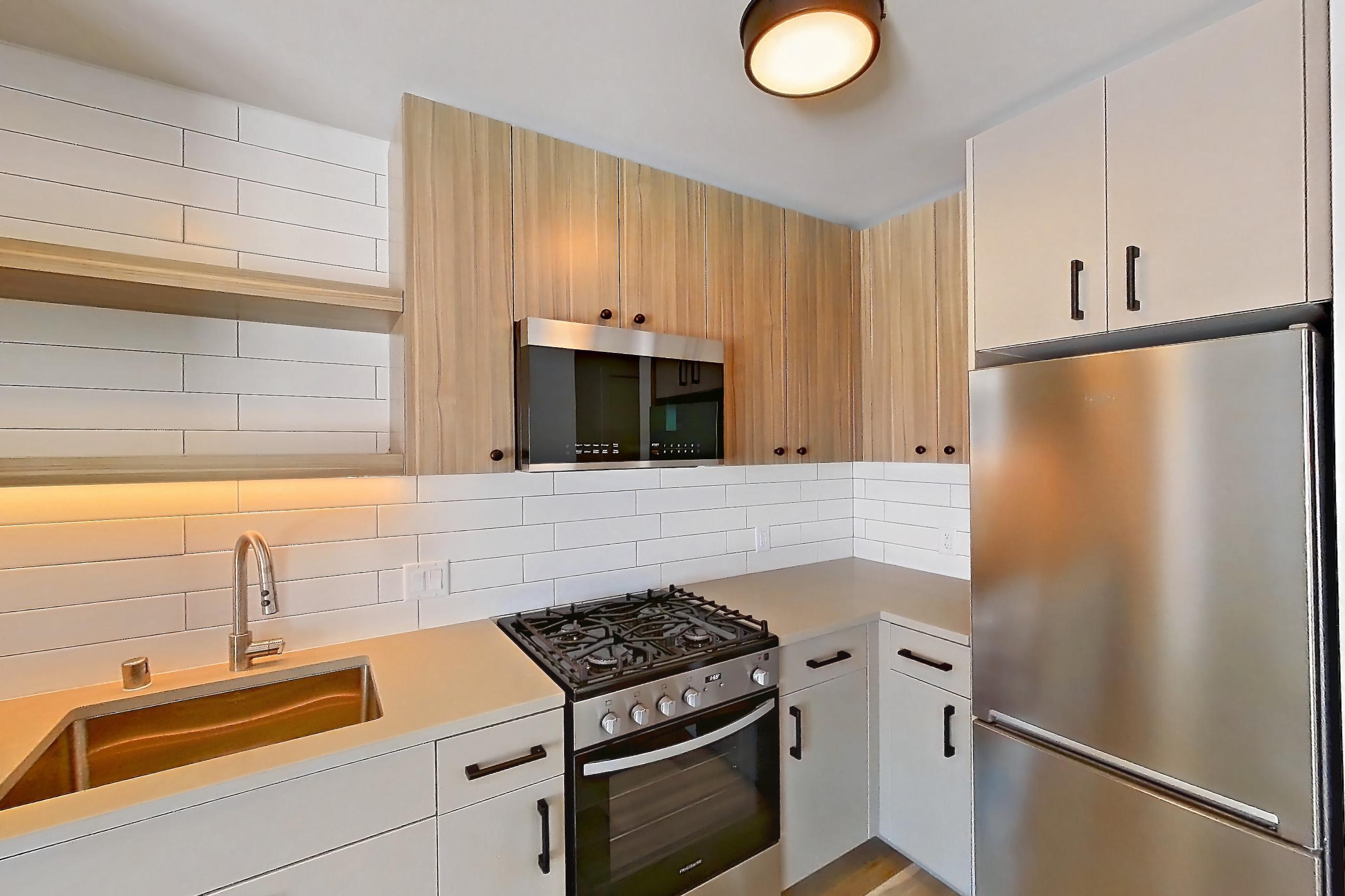 Kitchen with gas range, light countertops, light wood-finish flooring, oven/range, refrigerator, and stainless steel appliances, Apartment 720 at The Myles