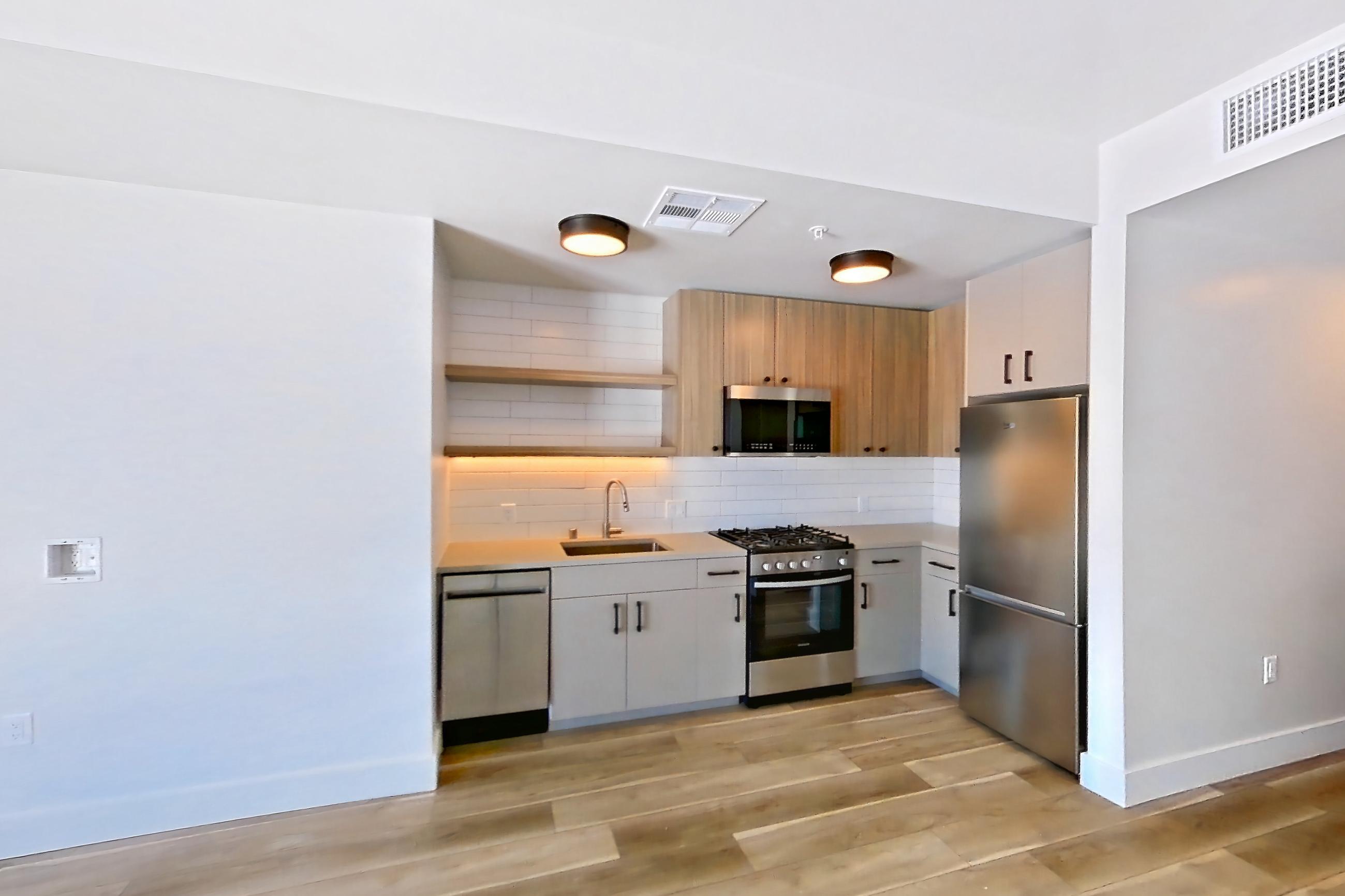 Living space with dishwasher, gas range, light countertops, light wood-finish flooring, oven/range, and stainless steel appliances, Apartment 720 at The Myles
