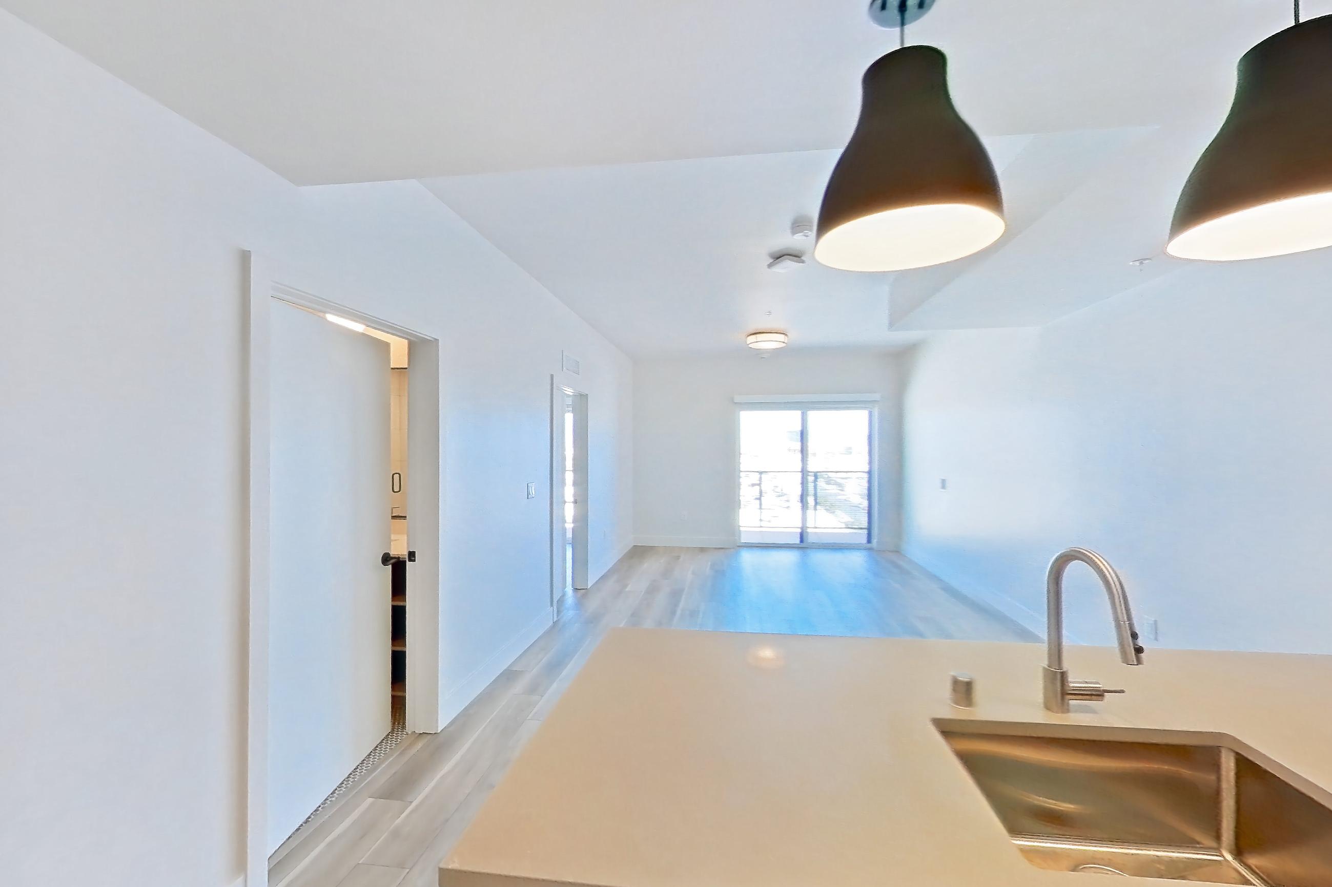 Kitchen with dishwasher, gas range, light countertops, light wood-finish flooring, microwave, oven/range, refrigerator, and stainless steel appliances, Apartment 722 at The Myles