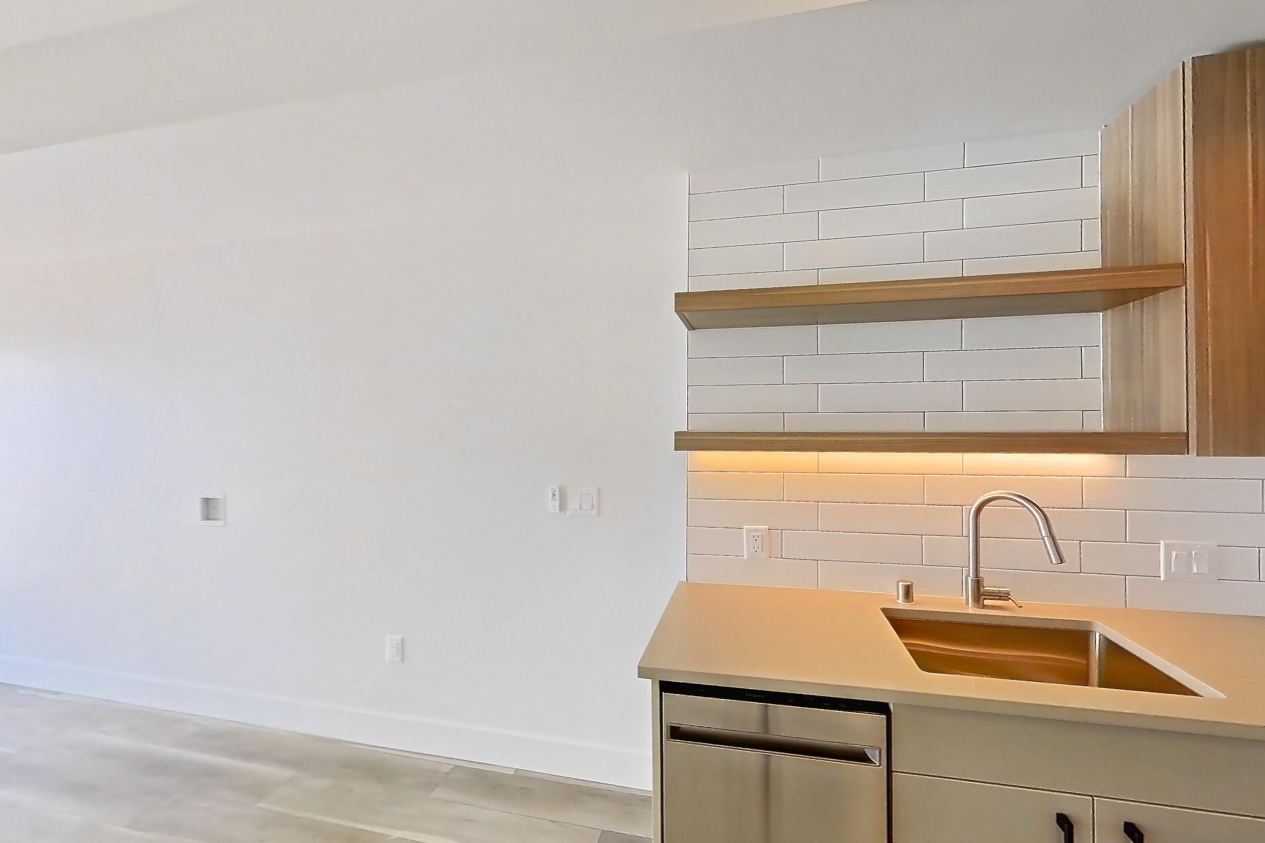 Kitchen with dishwasher, gas range, light countertops, light wood-finish flooring, oven/range, refrigerator, and stainless steel appliances, Apartment 726 at The Myles