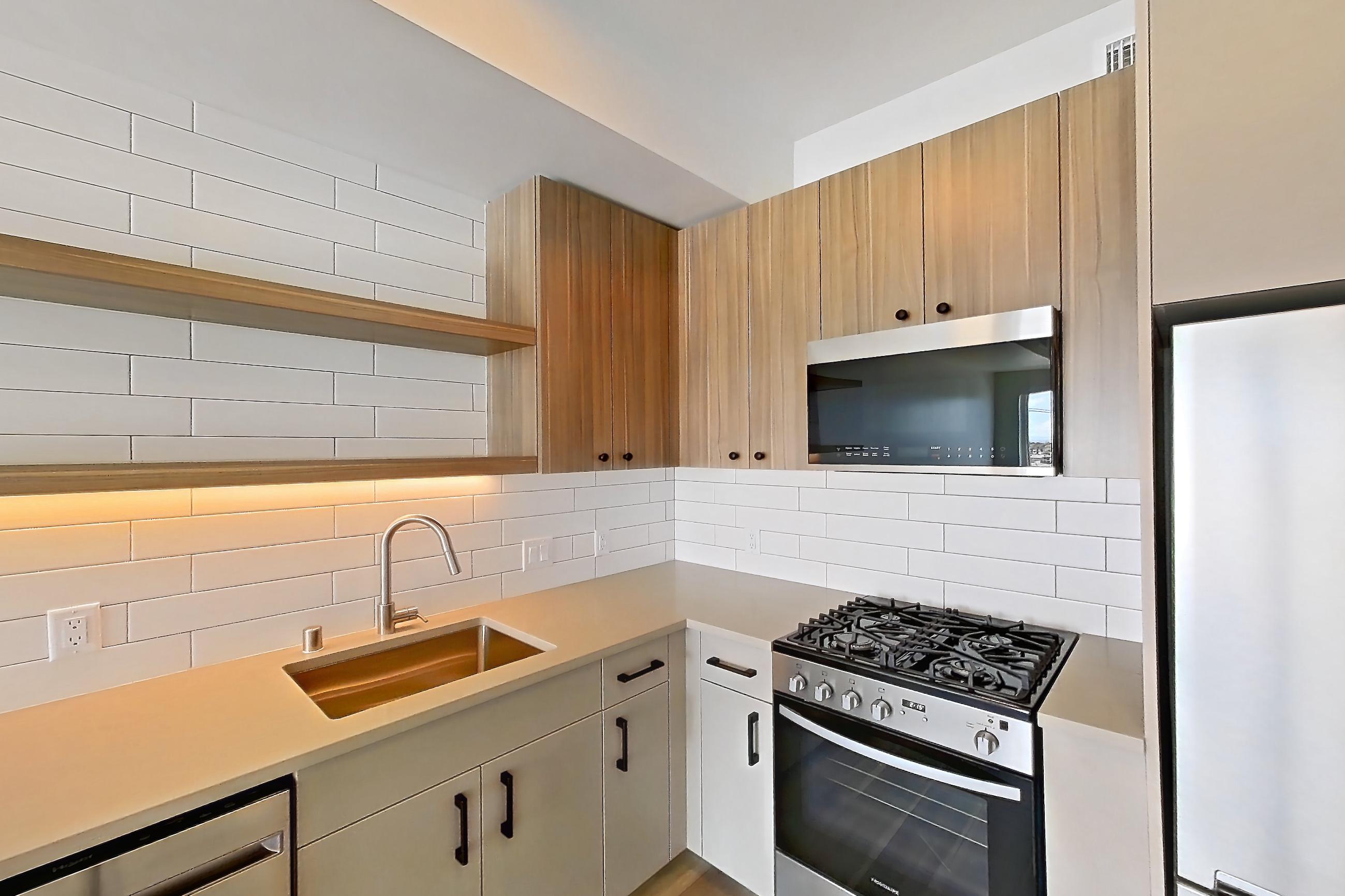 Kitchen with dishwasher, gas range, light countertops, light wood-finish flooring, oven/range, refrigerator, and stainless steel appliances, Apartment 726 at The Myles