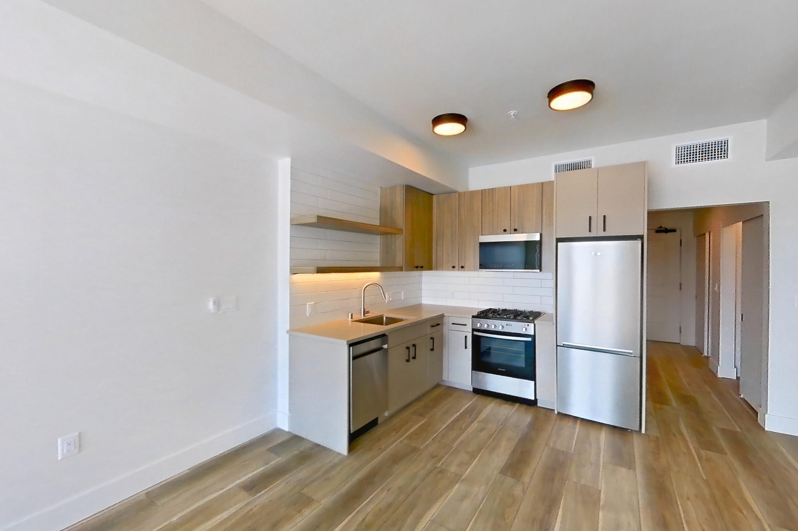 Living space with dishwasher, gas range, light countertops, light wood-finish flooring, oven/range, and stainless steel appliances, Apartment 726 at The Myles