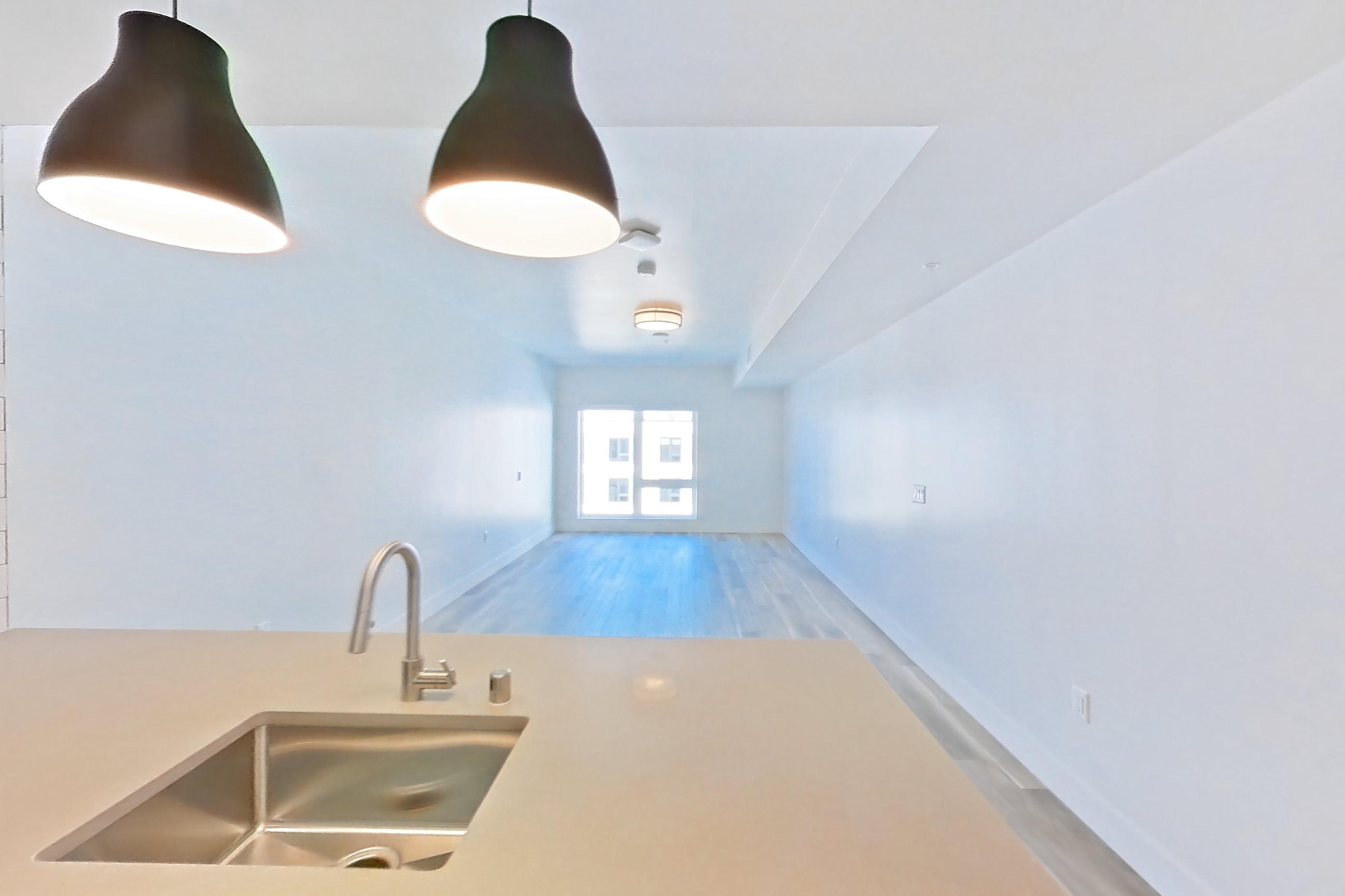 Kitchen with dishwasher, gas range, light countertops, light wood-finish flooring, oven/range, refrigerator, and stainless steel appliances, Apartment 727 at The Myles