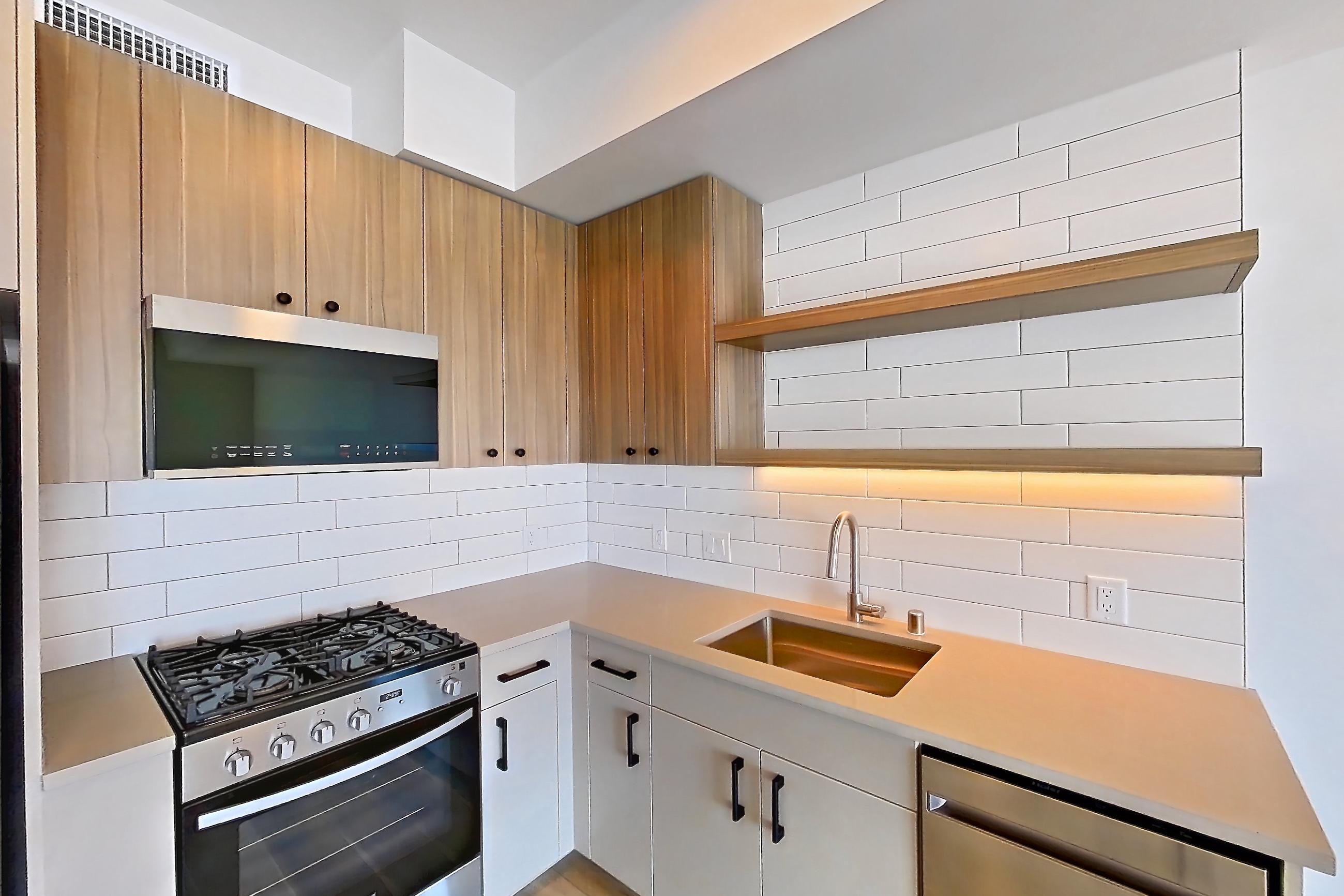 Kitchen with dishwasher, gas range, light countertops, light wood-finish flooring, oven/range, refrigerator, and stainless steel appliances, Apartment 728 at The Myles