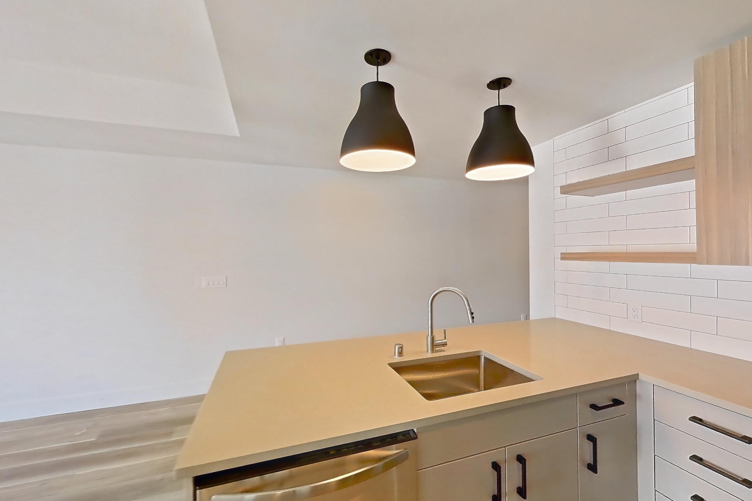 Kitchen with dishwasher, gas range, light countertops, light wood-finish flooring, microwave, oven/range, refrigerator, stainless steel appliances, and white appliances, Apartment 729 at The Myles