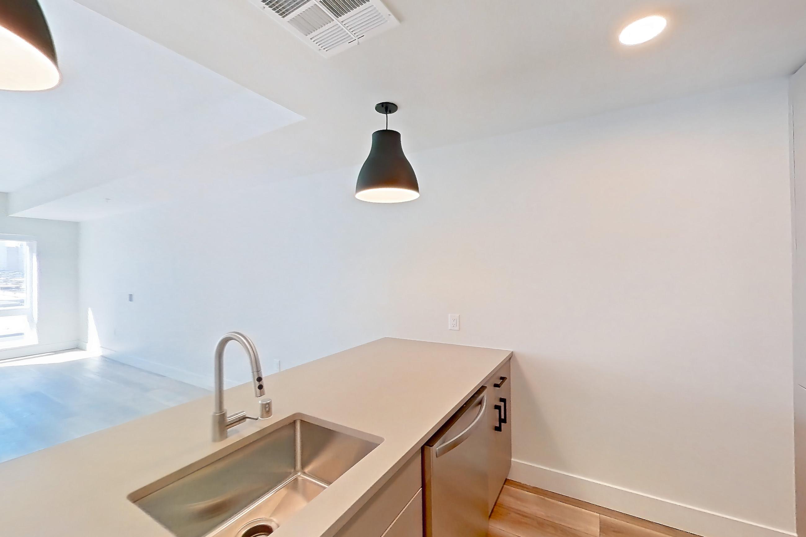 Kitchen with dishwasher, gas range, light countertops, light wood-finish flooring, oven/range, and stainless steel appliances, Apartment 736 at The Myles