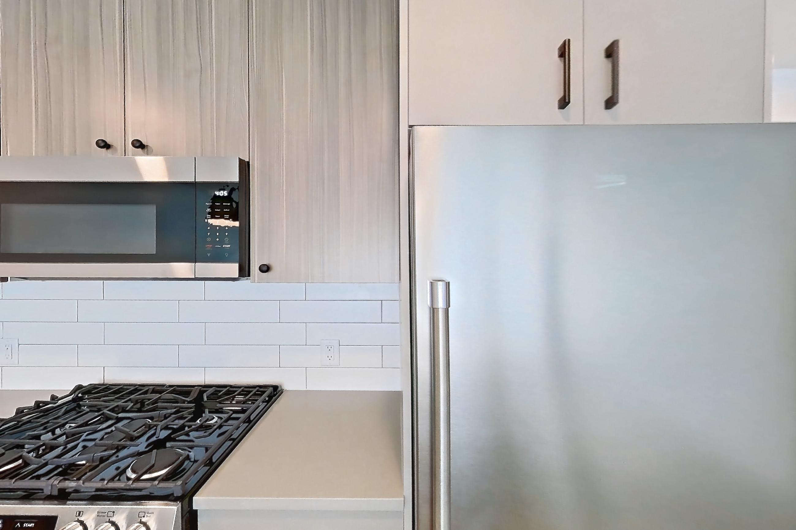 Kitchen with dishwasher, gas range, light countertops, light wood-finish flooring, oven/range, and stainless steel appliances, Apartment 736 at The Myles