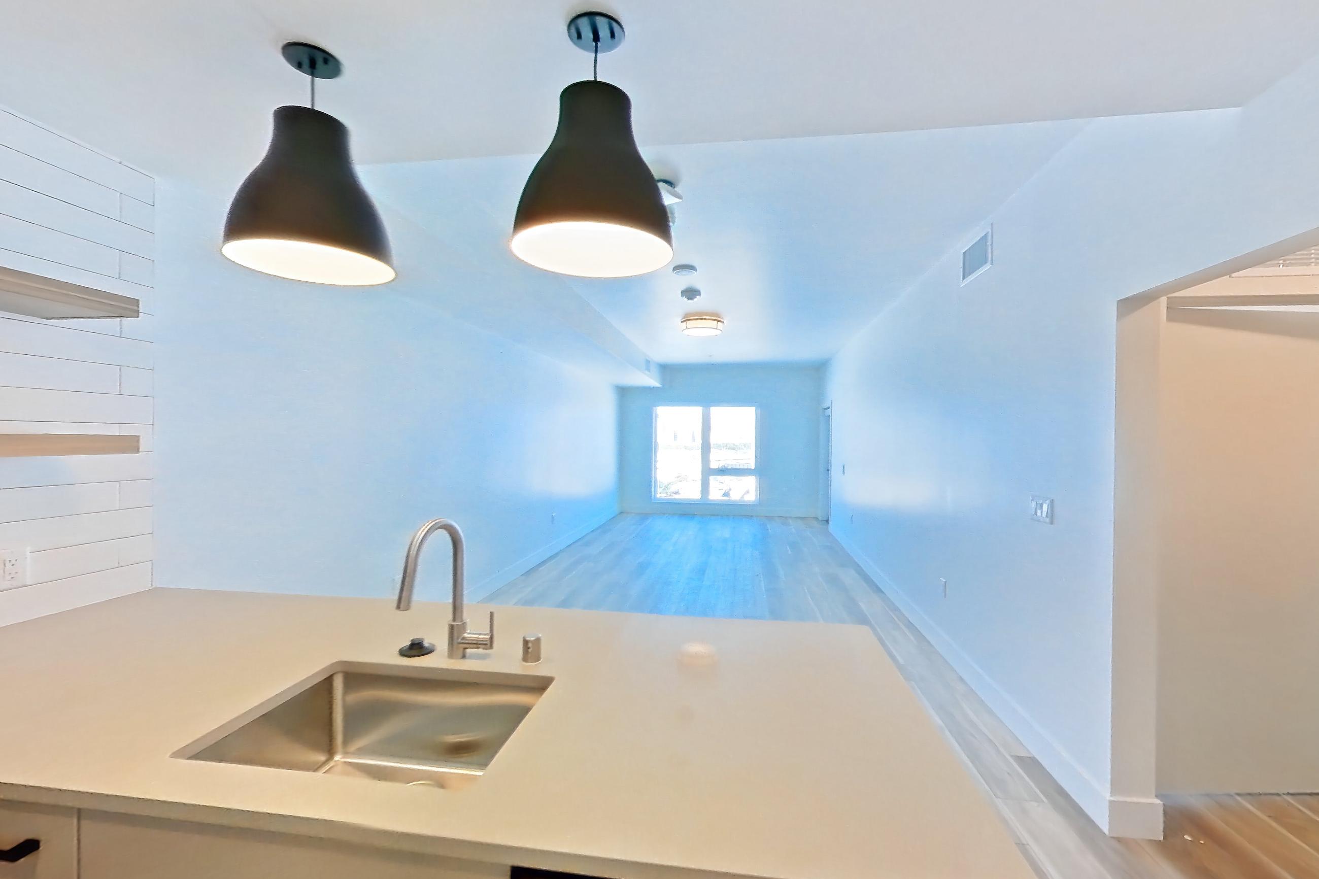 Kitchen with dishwasher, gas range, light countertops, light stone countertops, light wood-finish flooring, oven/range, refrigerator, and stainless steel appliances, Apartment 737 at The Myles