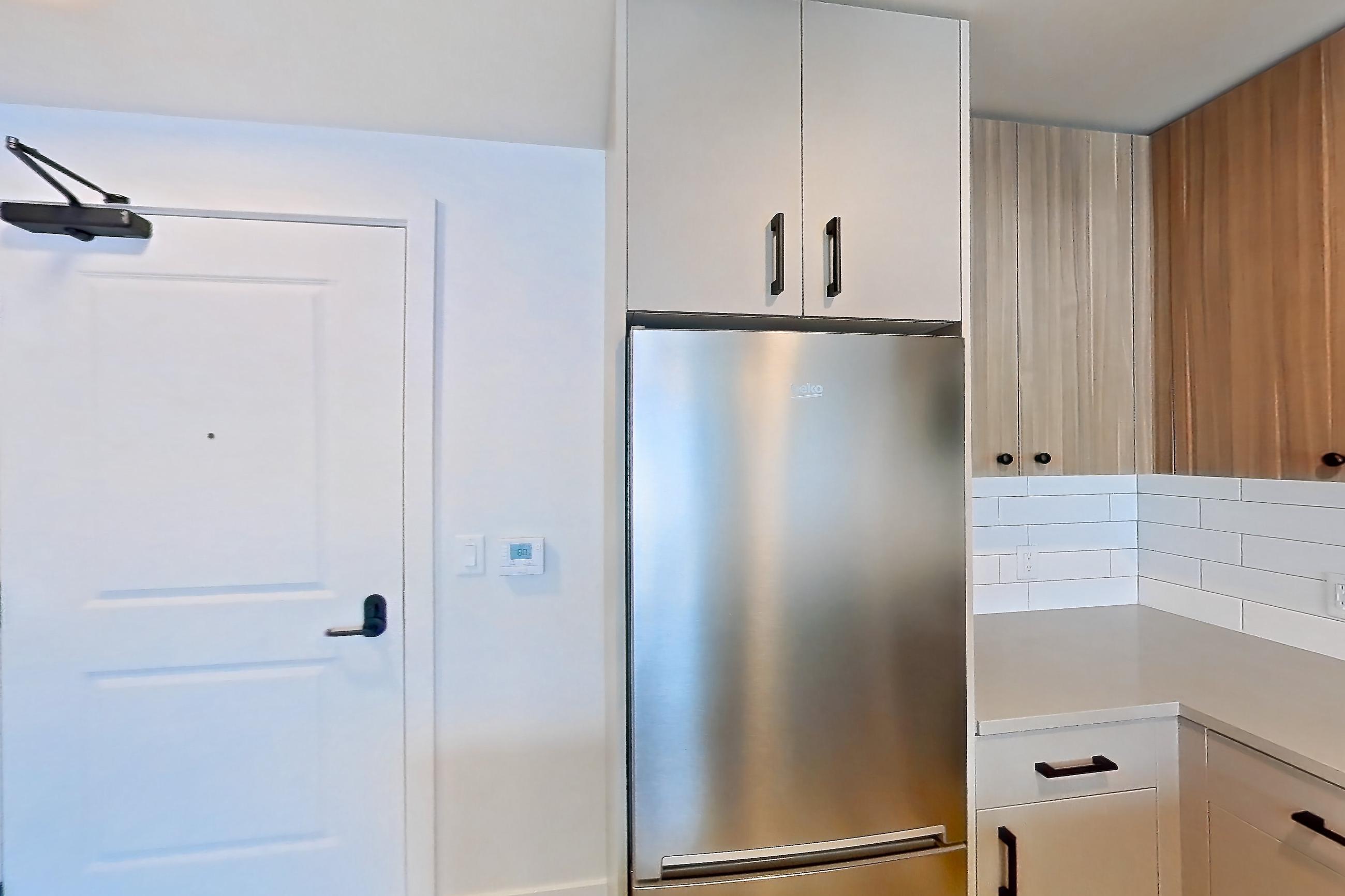 Kitchen with gas range, light countertops, light stone countertops, light wood-finish flooring, oven/range, refrigerator, and stainless steel appliances, Apartment 738 at The Myles