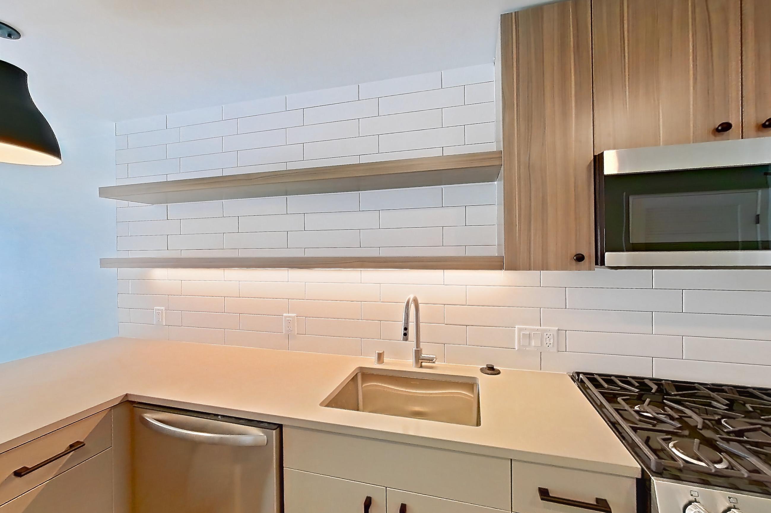Kitchen with dishwasher, gas range, light countertops, light wood-finish flooring, oven/range, refrigerator, and stainless steel appliances, Apartment 741 at The Myles