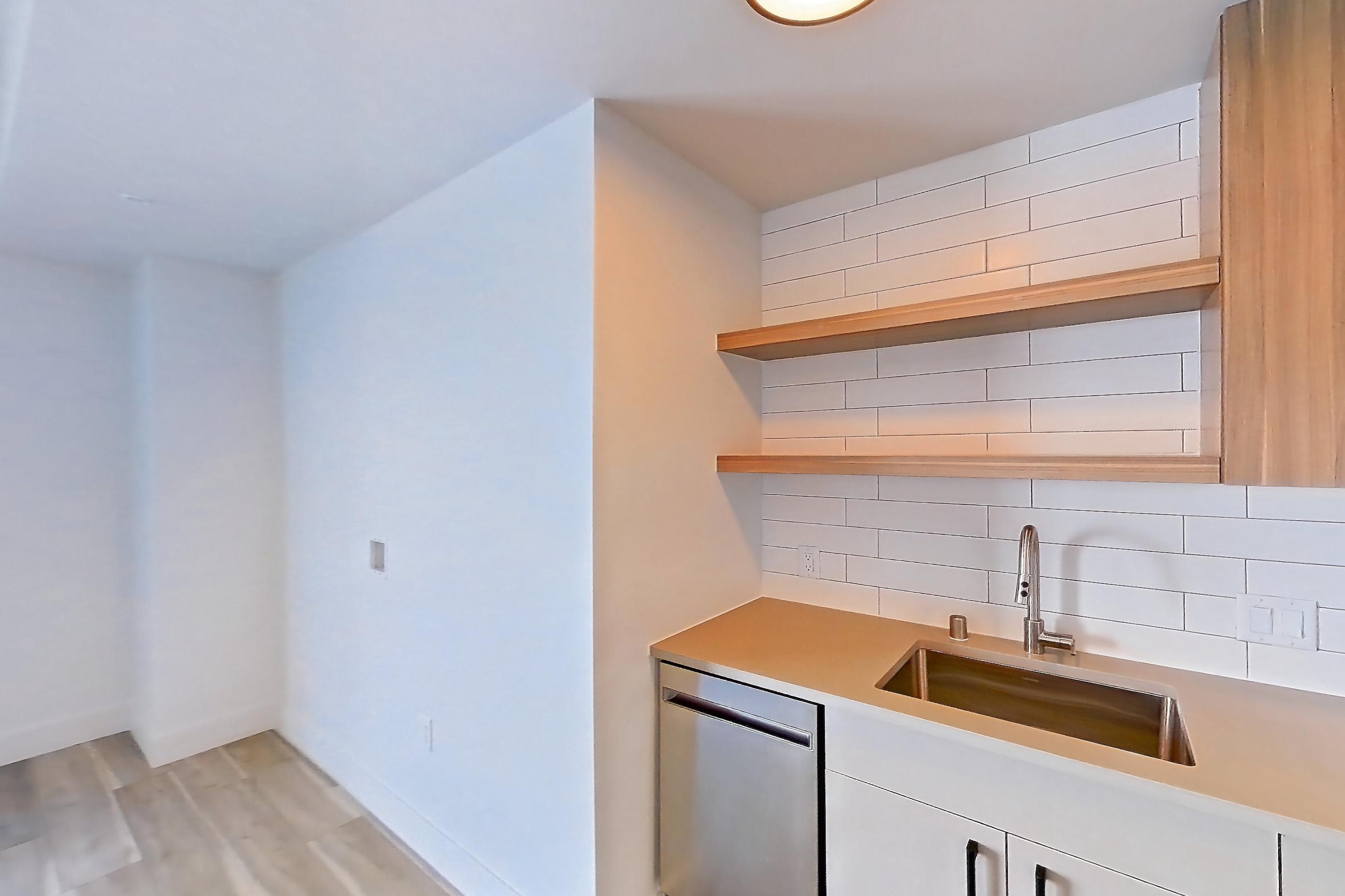 Kitchen with dishwasher, gas range, light countertops, light wood-finish flooring, oven/range, refrigerator, and stainless steel appliances, Apartment 743 at The Myles