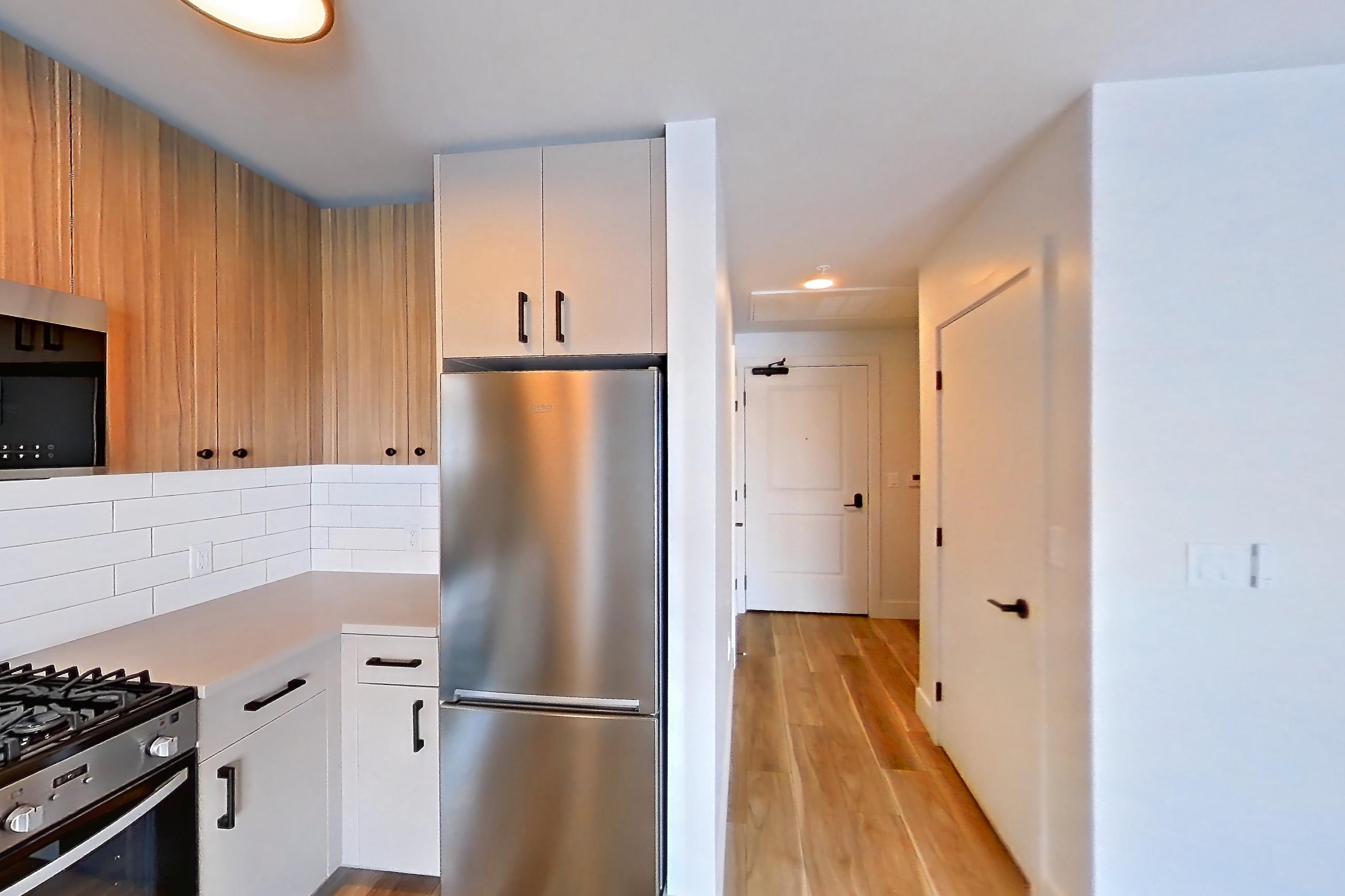 Kitchen with dishwasher, gas range, light countertops, light wood-finish flooring, oven/range, refrigerator, and stainless steel appliances, Apartment 743 at The Myles
